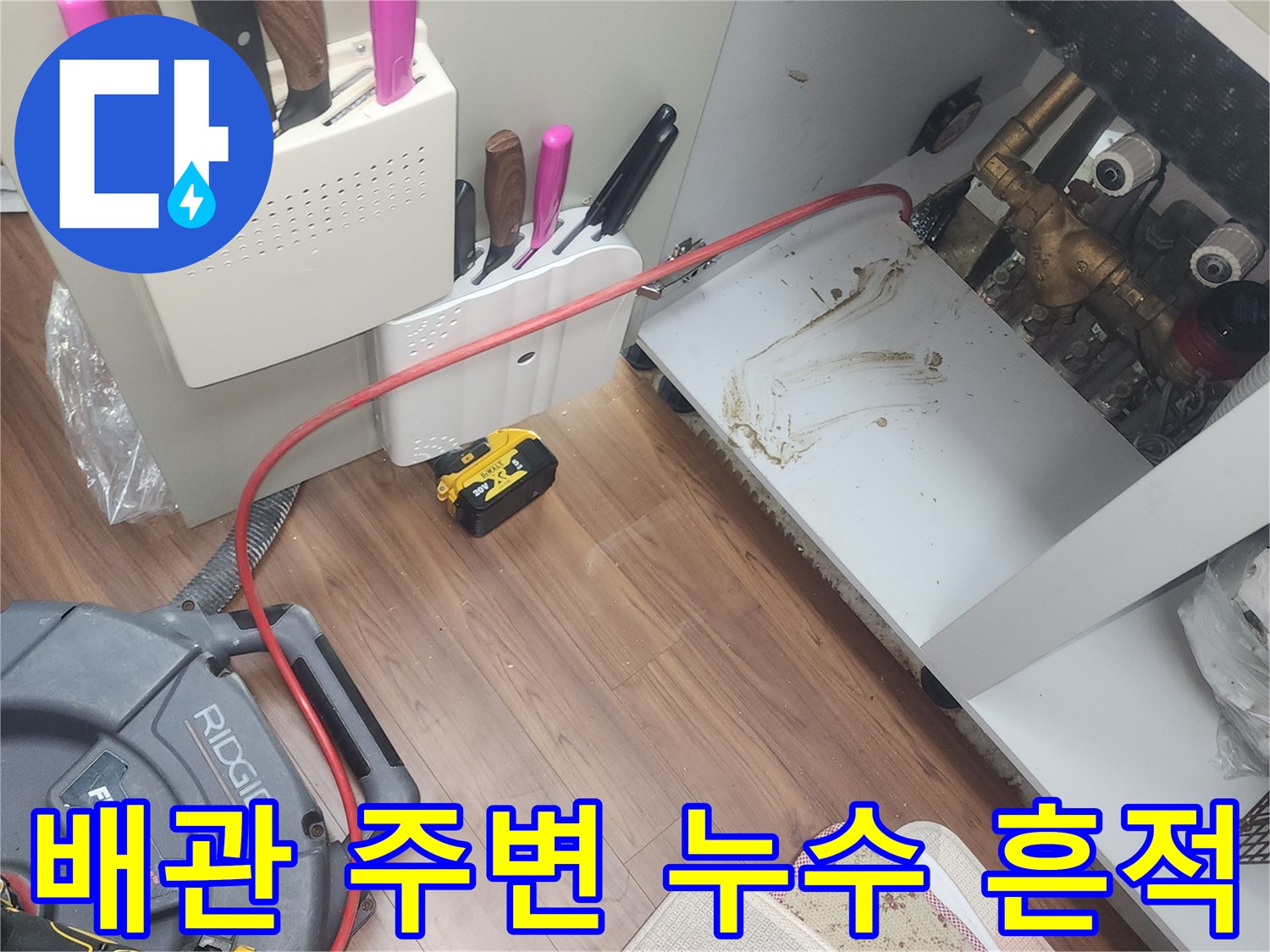싱크대 배관 주변의 젖은 자국과 오염된 바닥 상태를 나타냅니다.