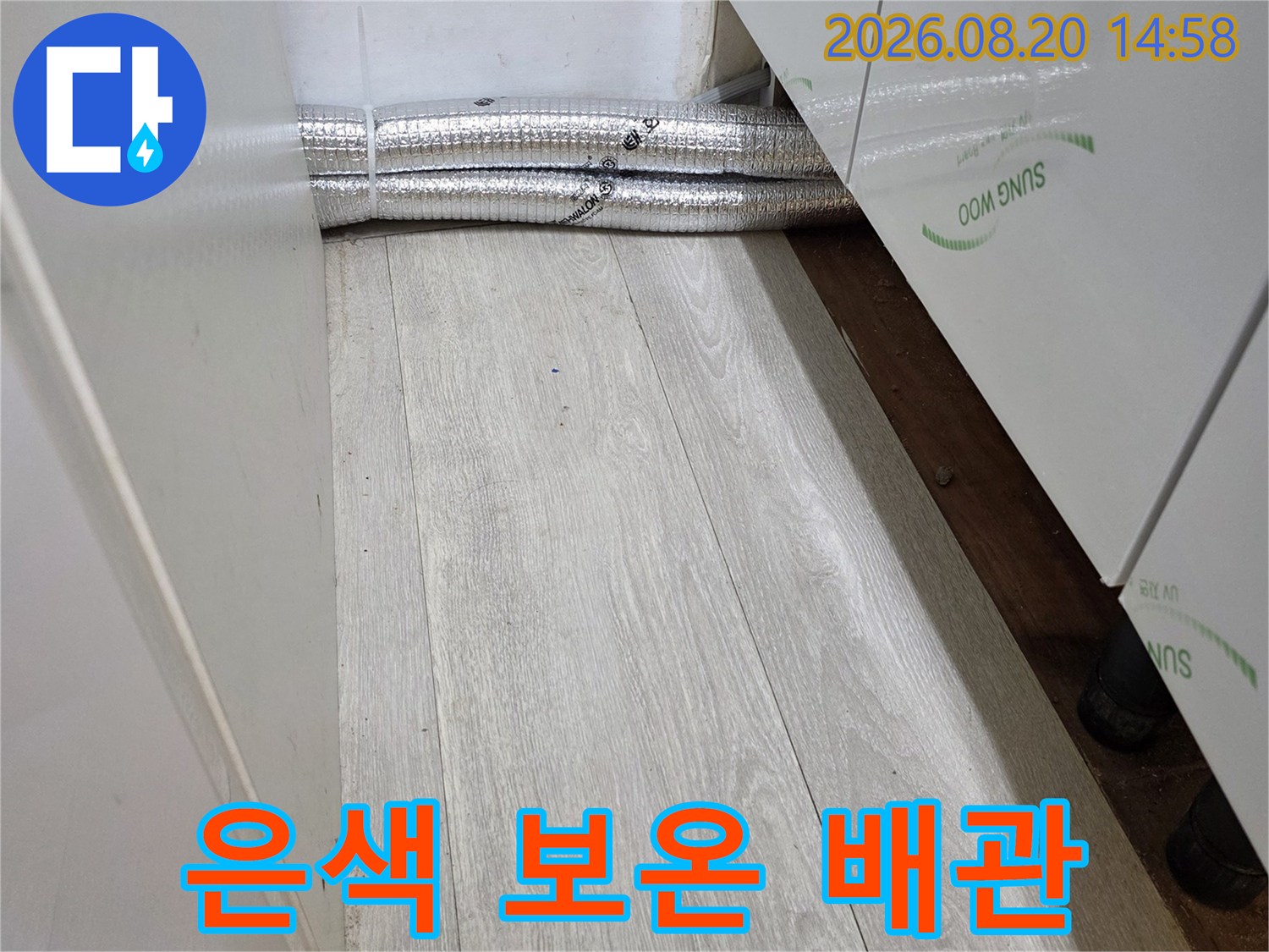 보온재로 감싸진 배관이 벽면과 마루 경계에 있는 모습