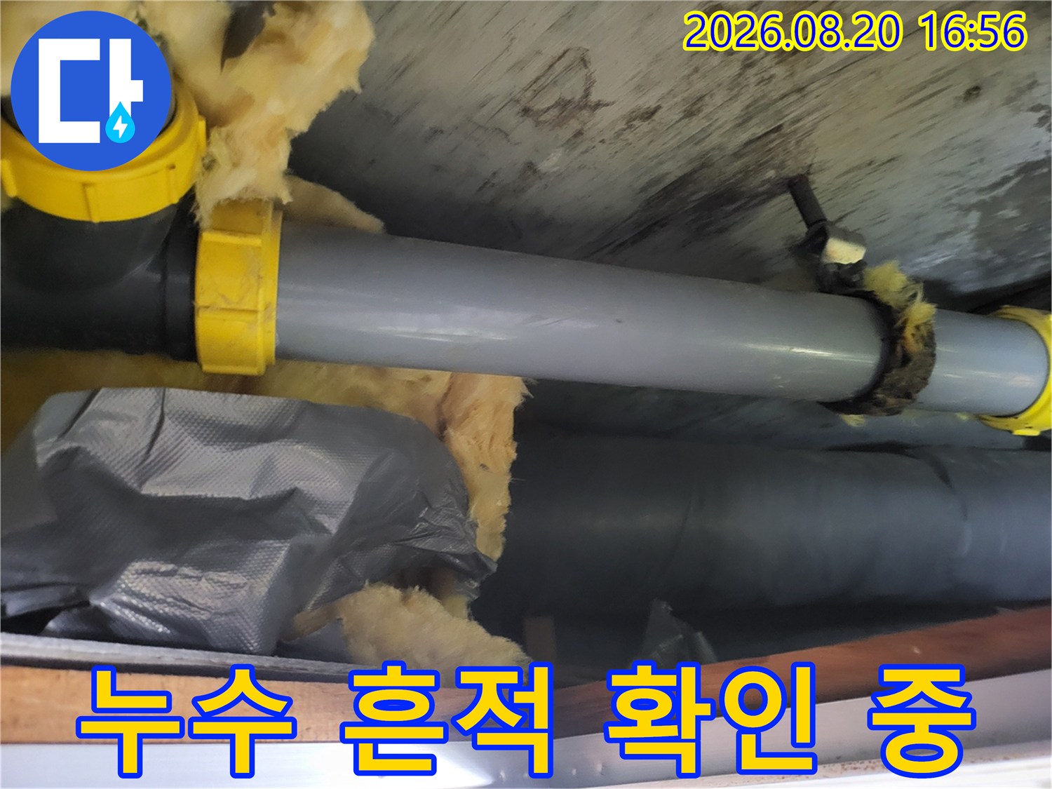 천장 내부의 젖은 단열재와 배관 연결 부위를 근접 촬영했습니다.