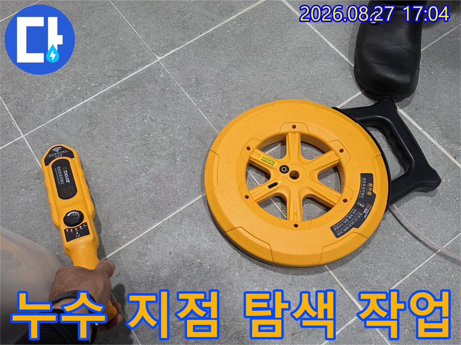 회색 욕실 타일 위에서-배관 탐지기로 누수 위치를 찾는 모습