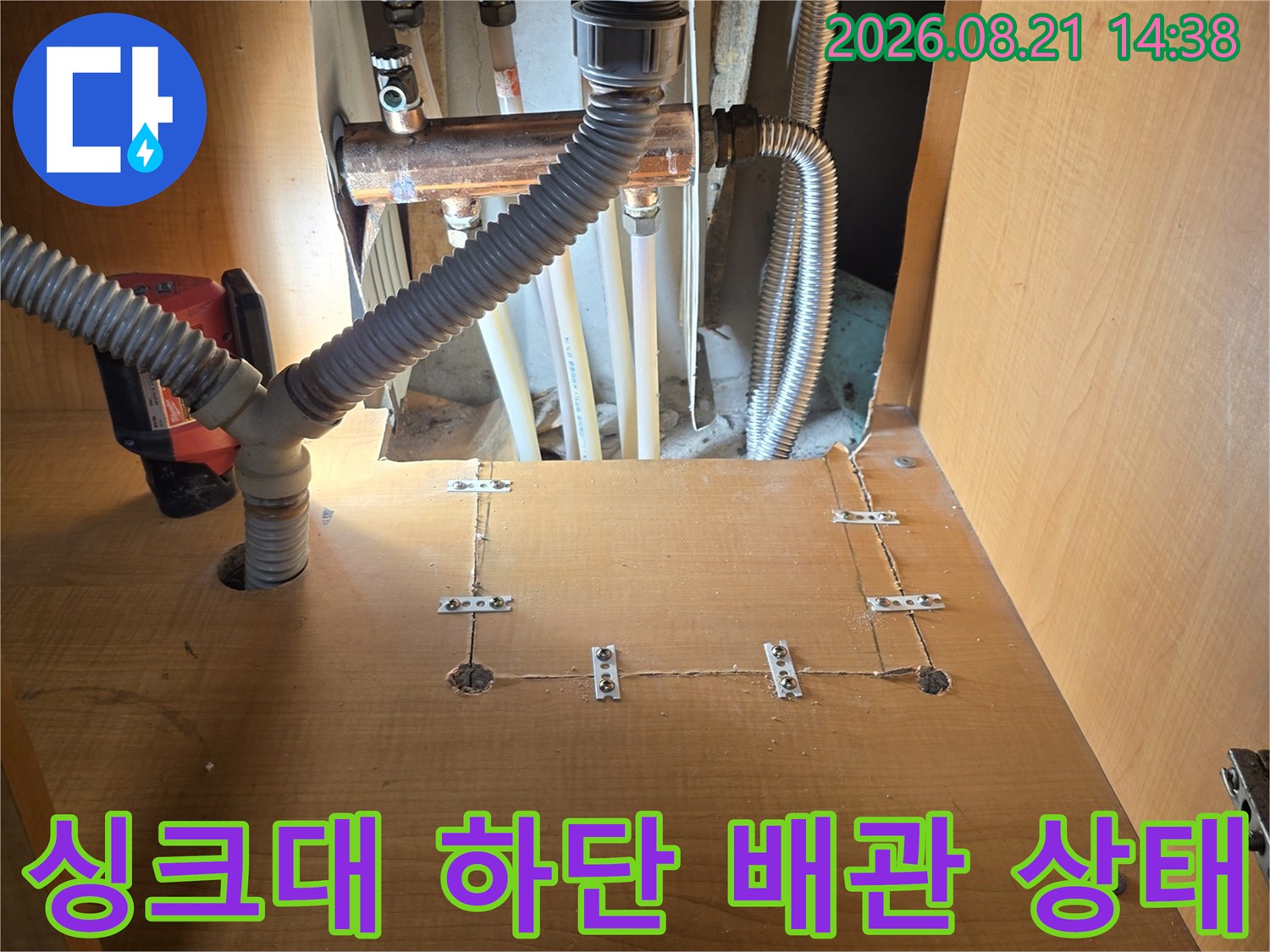 싱크대 아래쪽의 금속 배관과 회색 주름관 연결 부위
