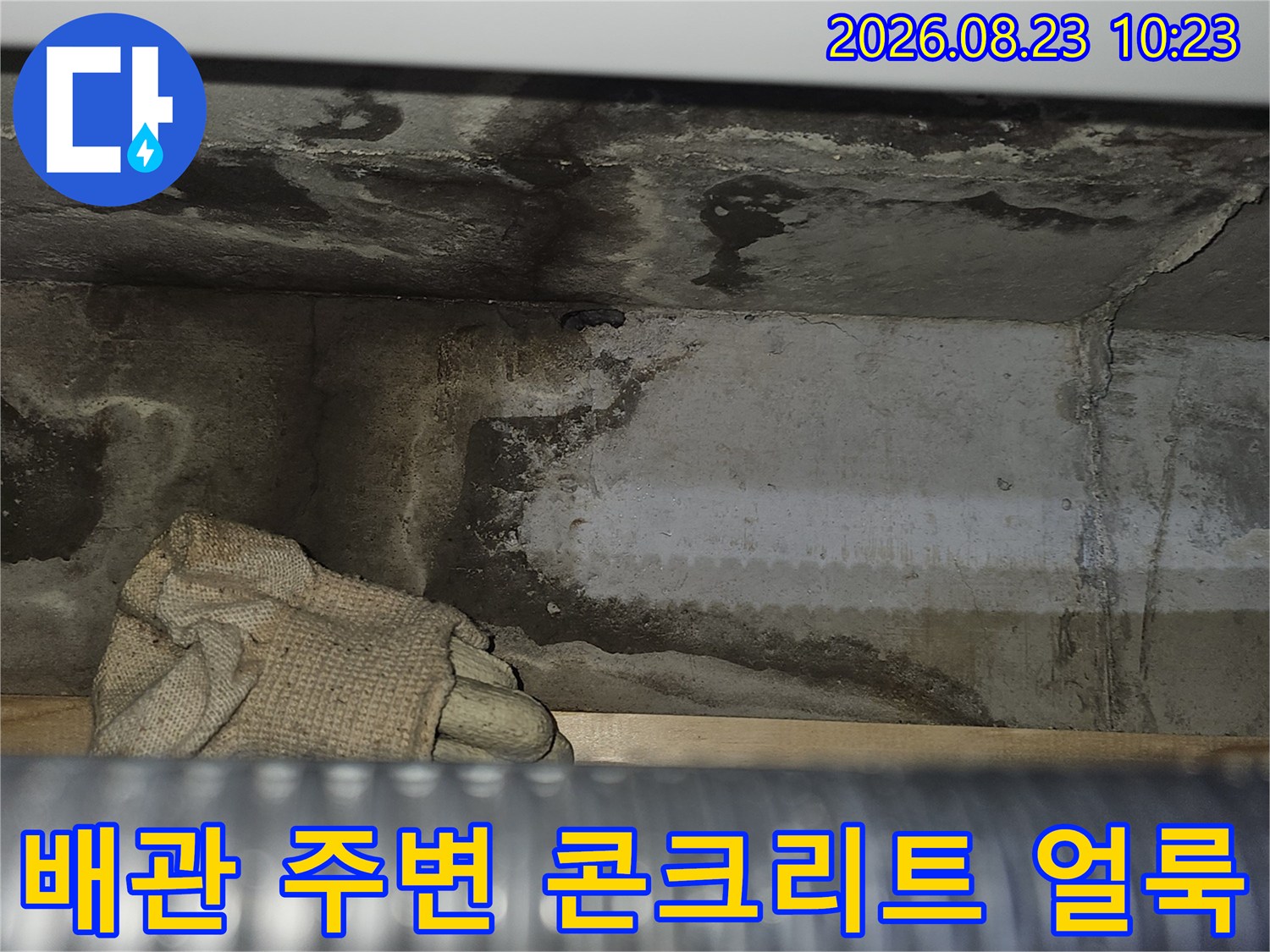 천장 배관 근처 콘크리트 면에 나타난 젖은 흔적과 어두운 변색 부위