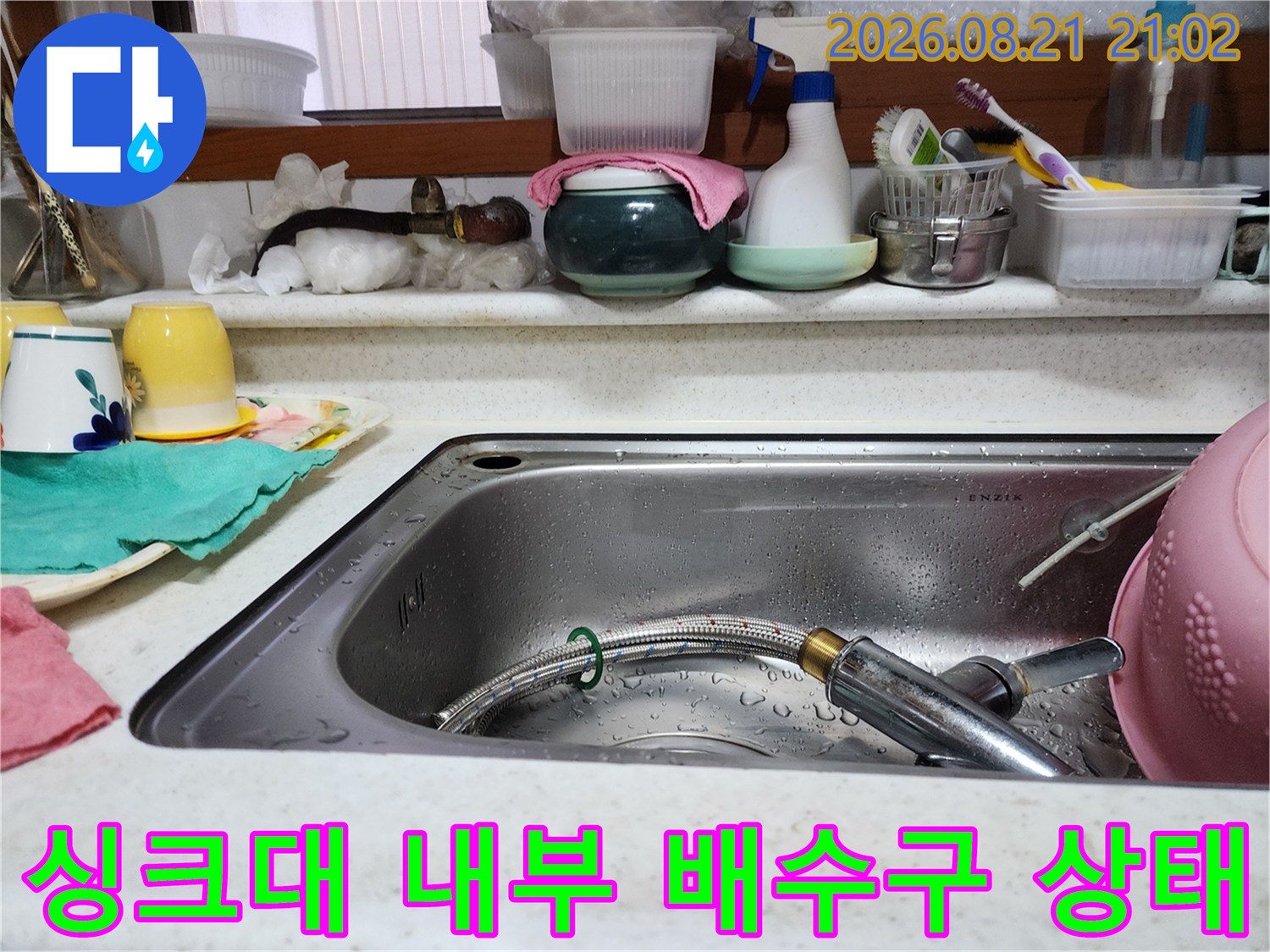 물이 고여 있는 스테인리스 싱크대와 수전 호스
