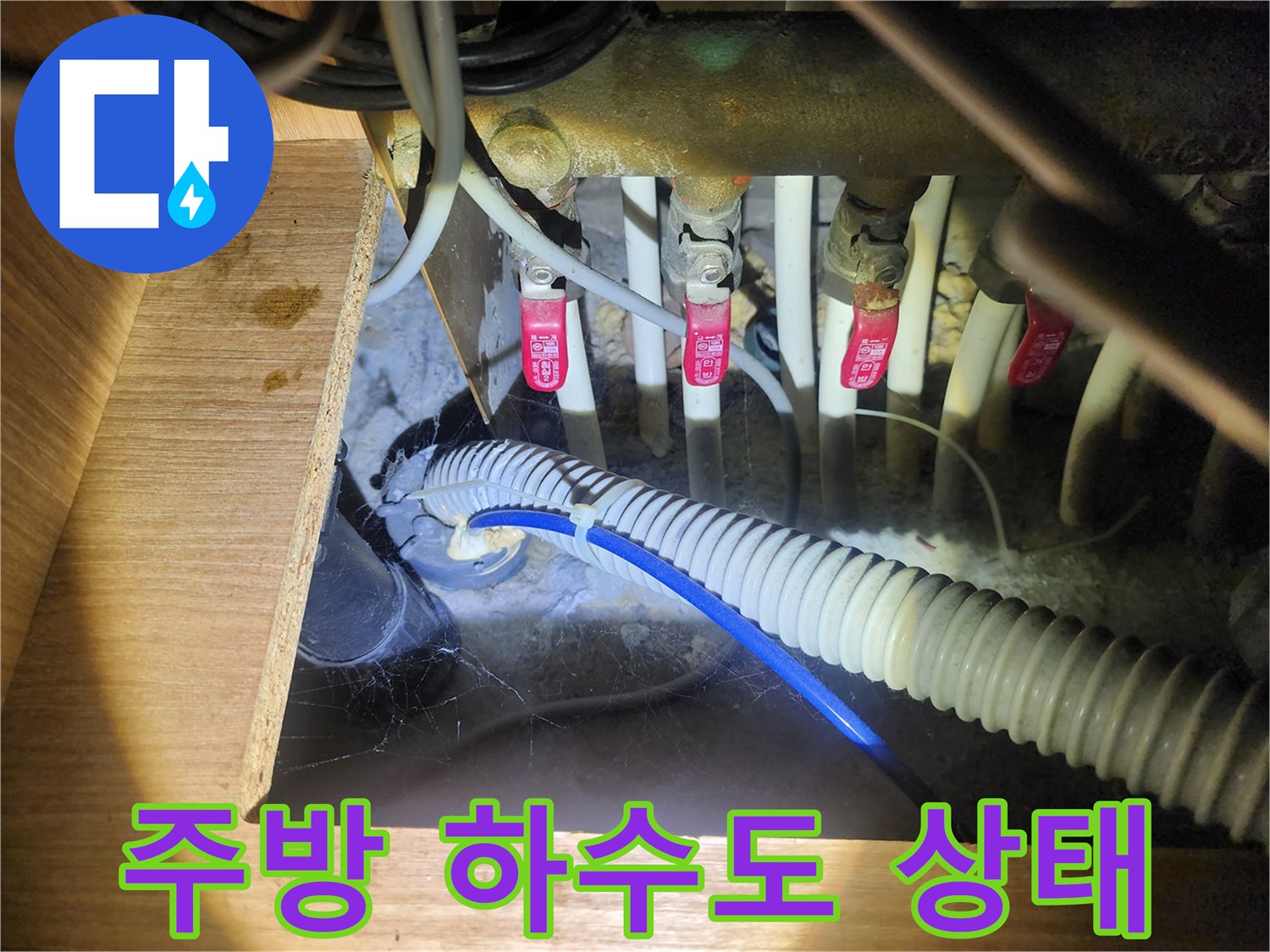 하부장 내부에 노출된 급수 밸브와 배수 호스 연결 부위