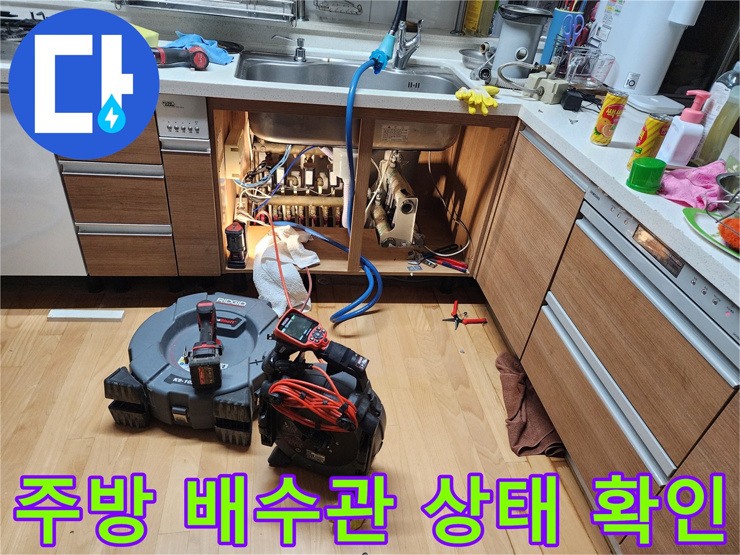 싱크대 하부장 내부의 복잡한 배관과 작업용 장비들