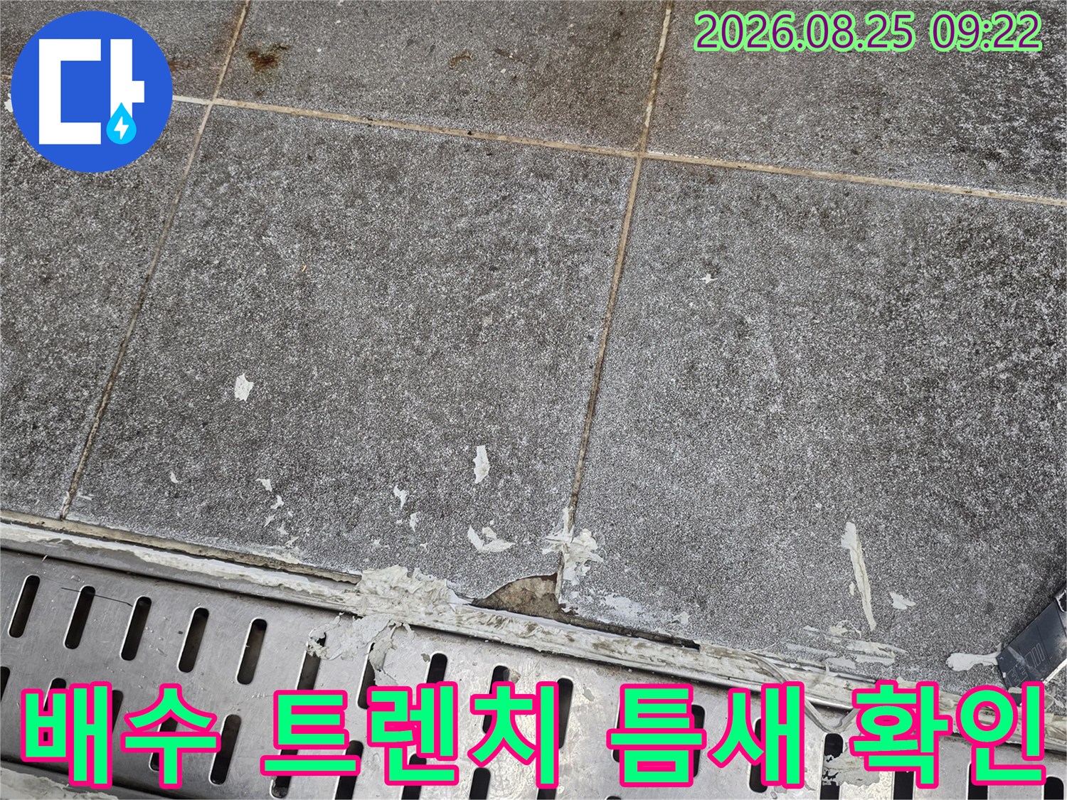 금속 배수 트렌치-주변 타일의 벌어진 틈을 상세하게 보여주는 사진입니다.