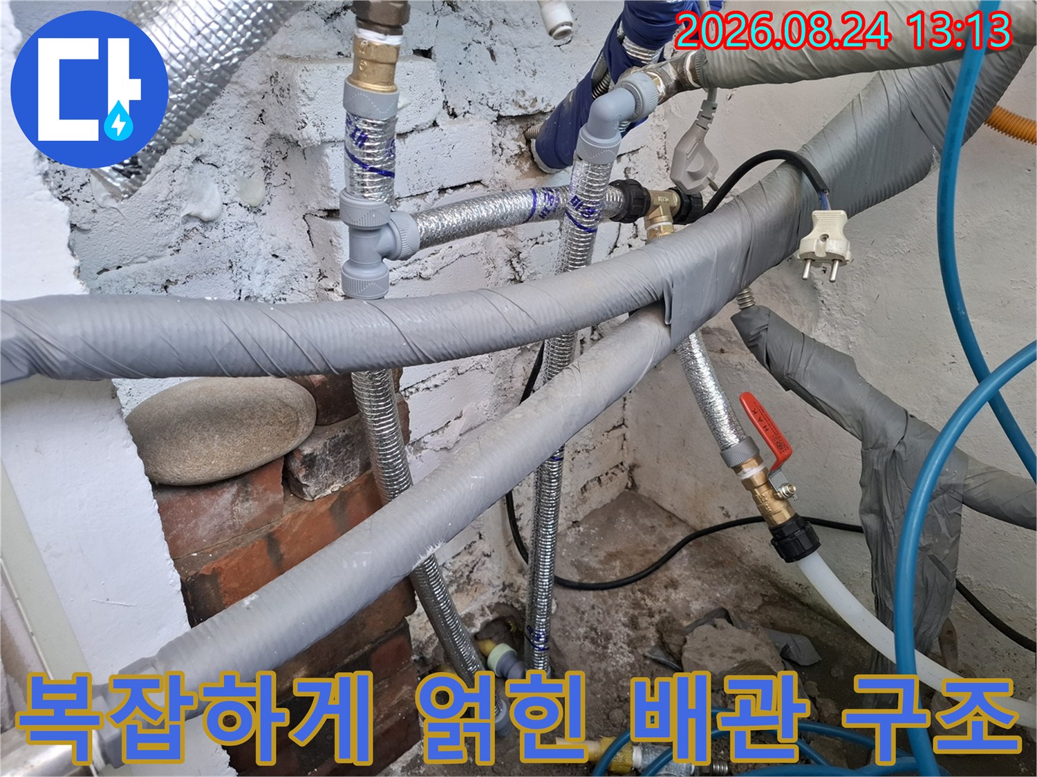 보일러실 내부의 은색 보온재와 파란색 호스가 연결된 모습