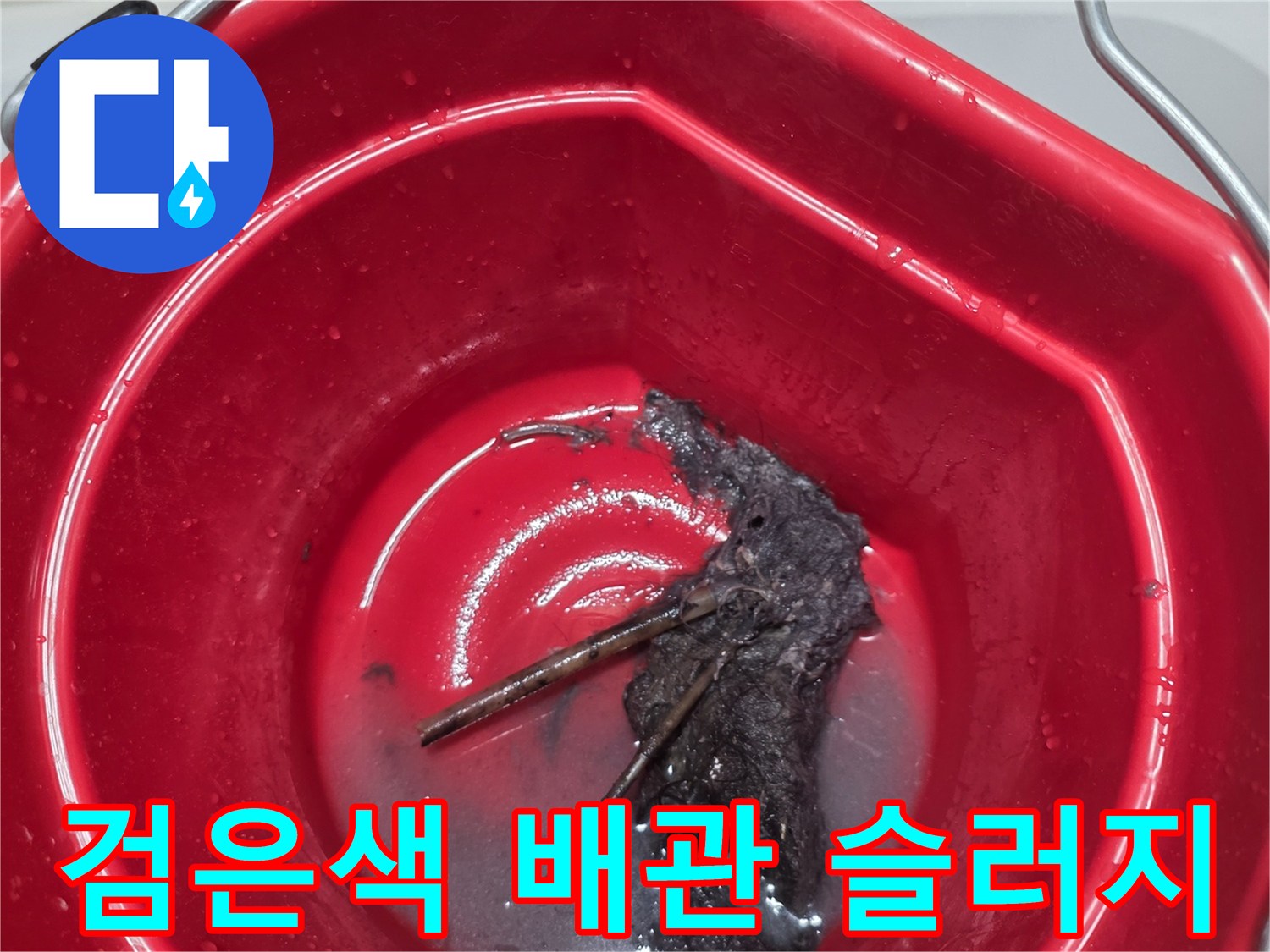 빨간 양동이 속의 검고 걸쭉한 배관 오염 물질