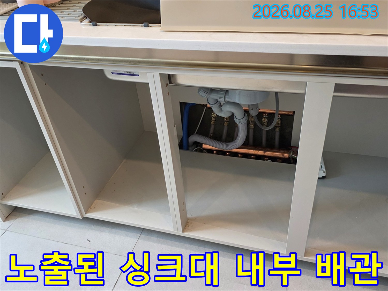 싱크대 아래 공간에 드러난 배수 호스와 연결 배관의 근접 촬영