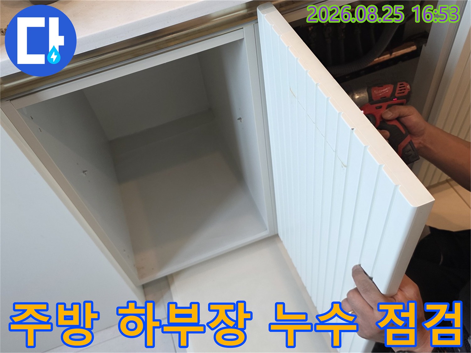 싱크대 아래쪽 배관 연결 부위를 손으로 직접 확인하며 점검하고 있습니다.