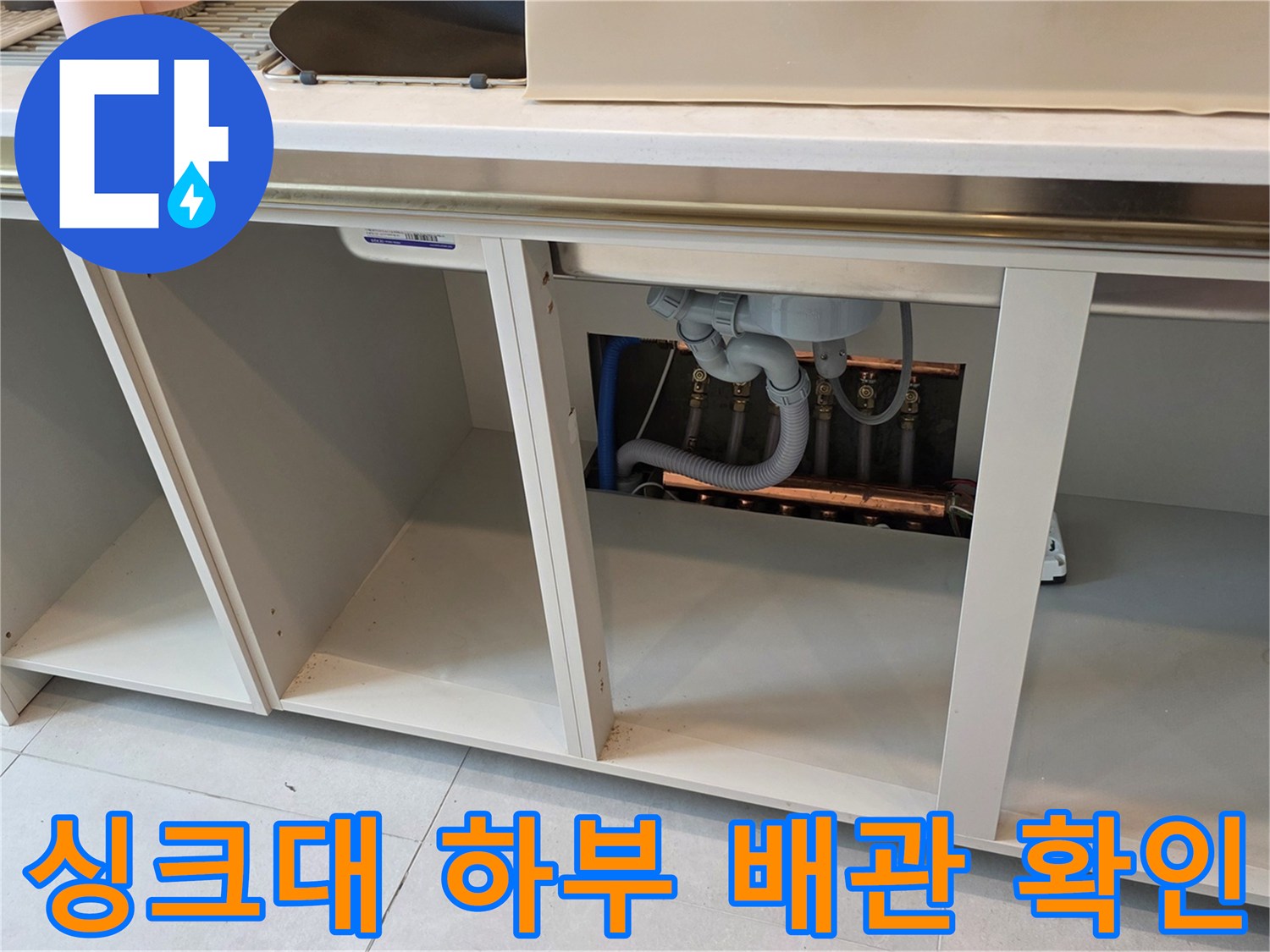 싱크대 아래쪽-배관이 노출되어 있는 내부 점검 현장 사진입니다.