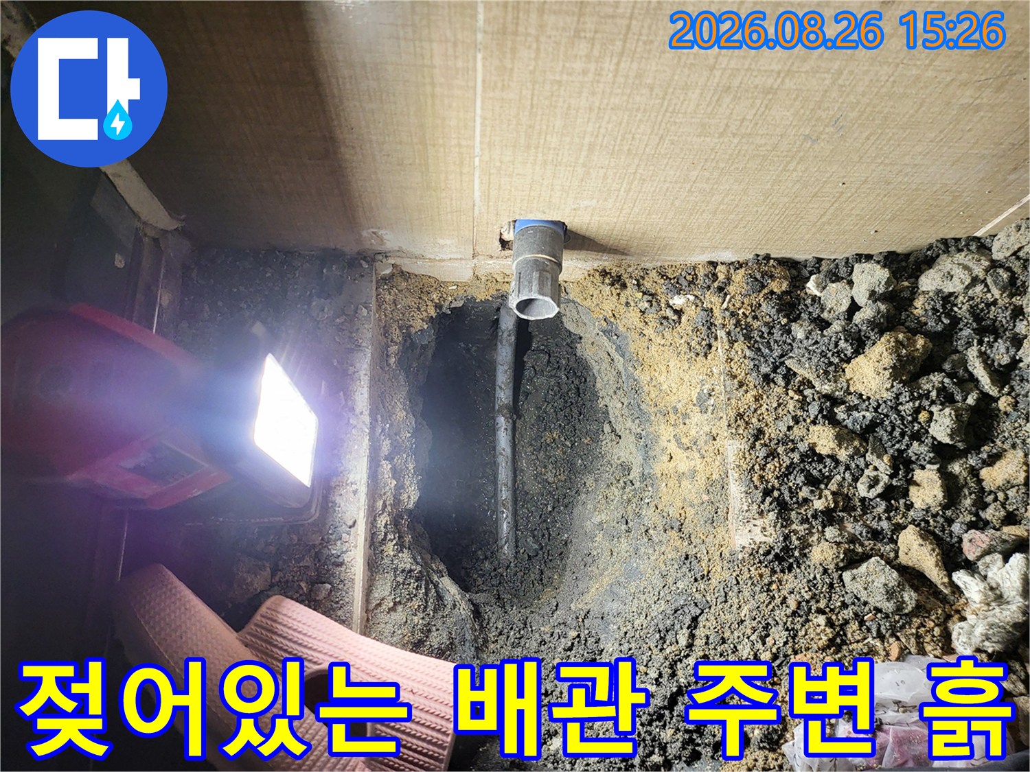 축축하게 젖은 오수 배관 하단부와 주변 자갈층