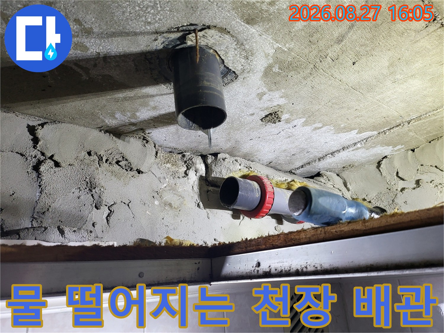 천장 구조물에 설치된 수직 배관에서 물이 새는 모습