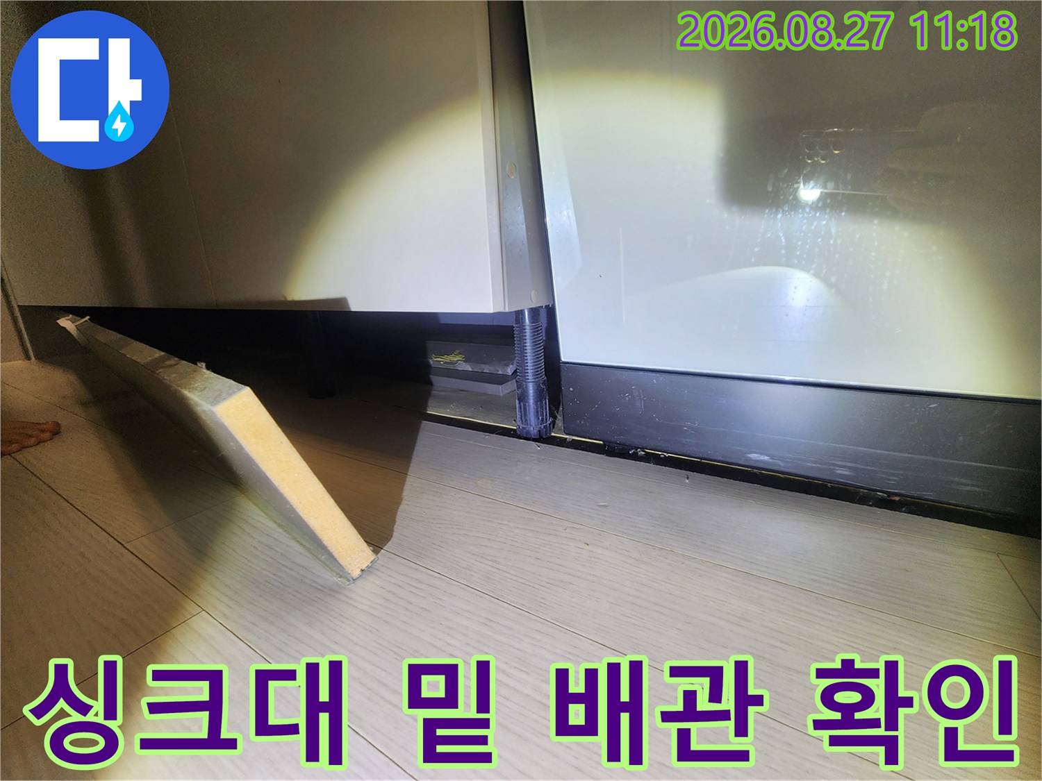 싱크대 하단 공간-배관 연결 부위를 정밀하게 조사하는 장면