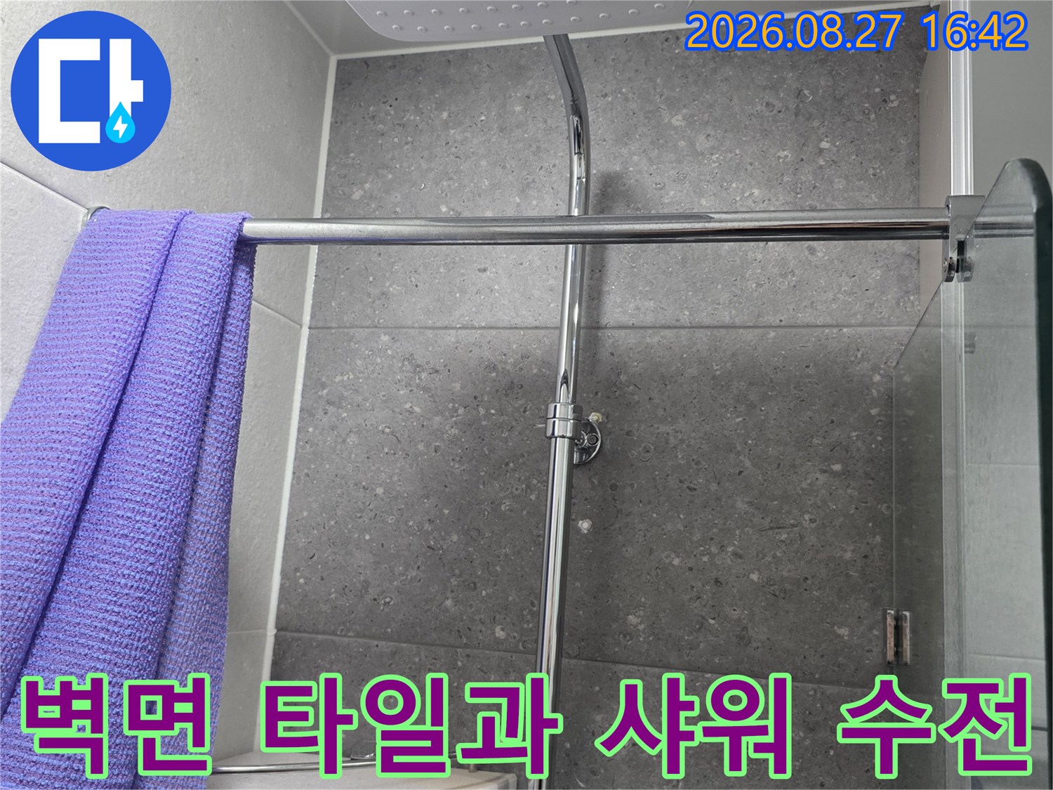 회색 타일 벽면에 설치된 금속 재질의 샤워기 수전대