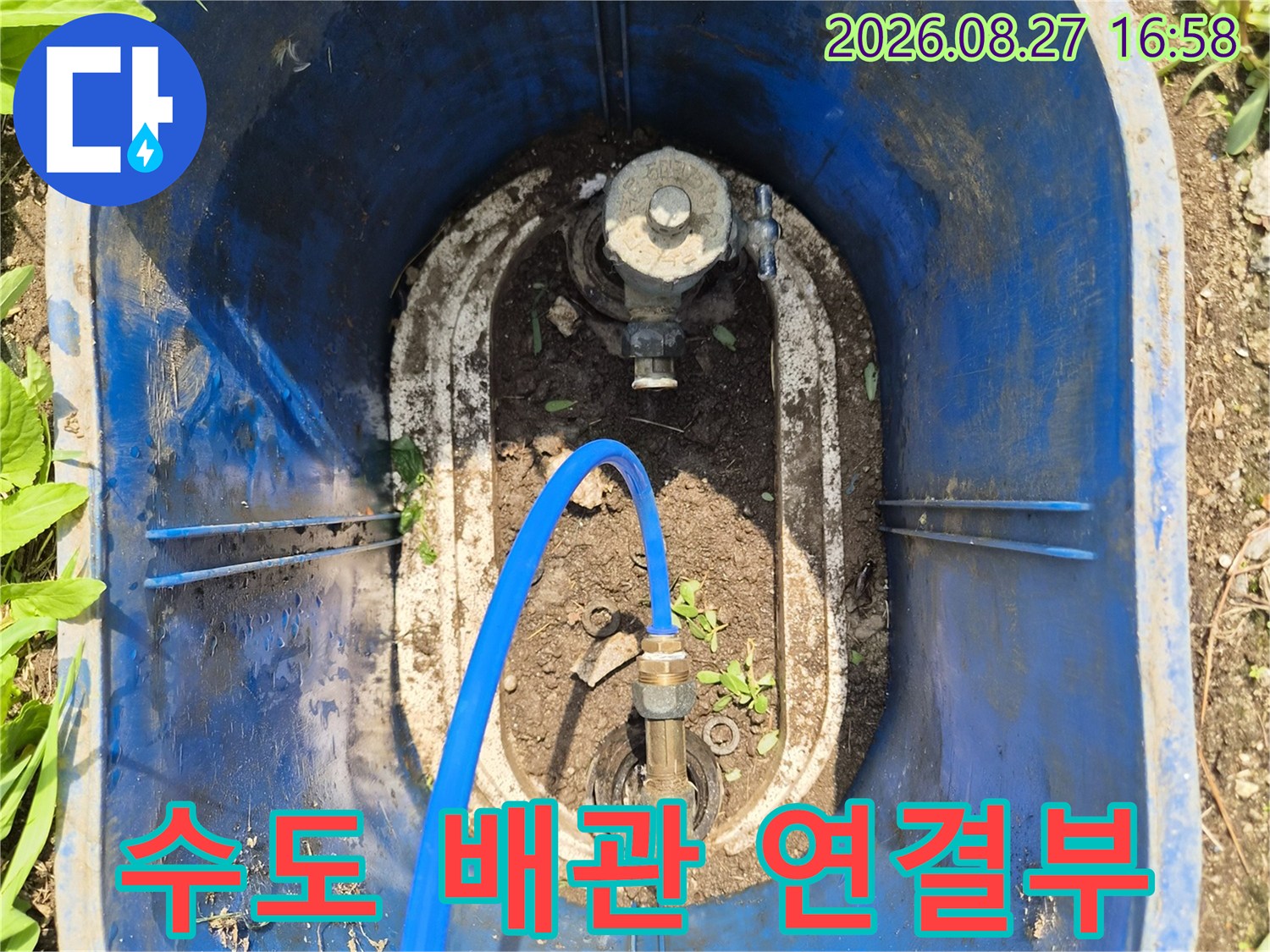흙이 묻은 배관 부속에 파란색 호스가 연결된 모습