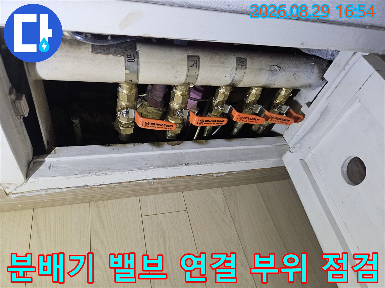 상계동 아파트 분배기의 주황색 핸들과 금속 배관 상세 사진