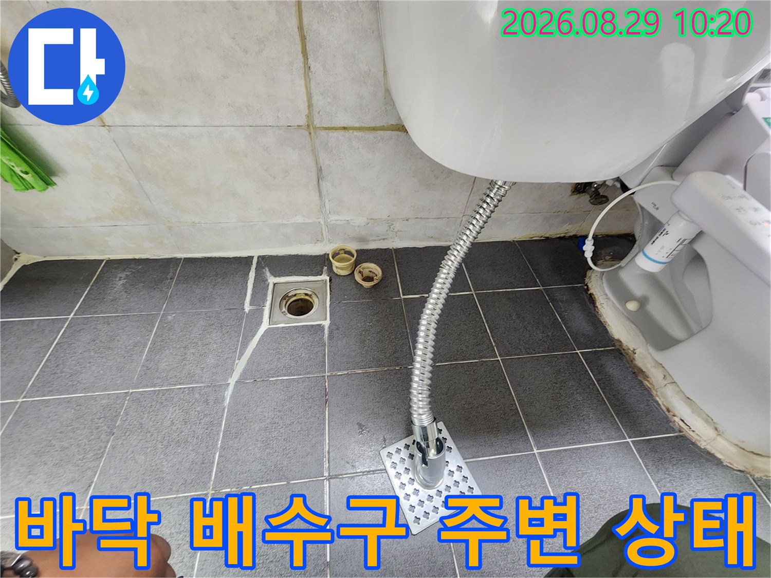 타일 바닥에 위치한 배수구와 세면대 배관의 연결 부위입니다.