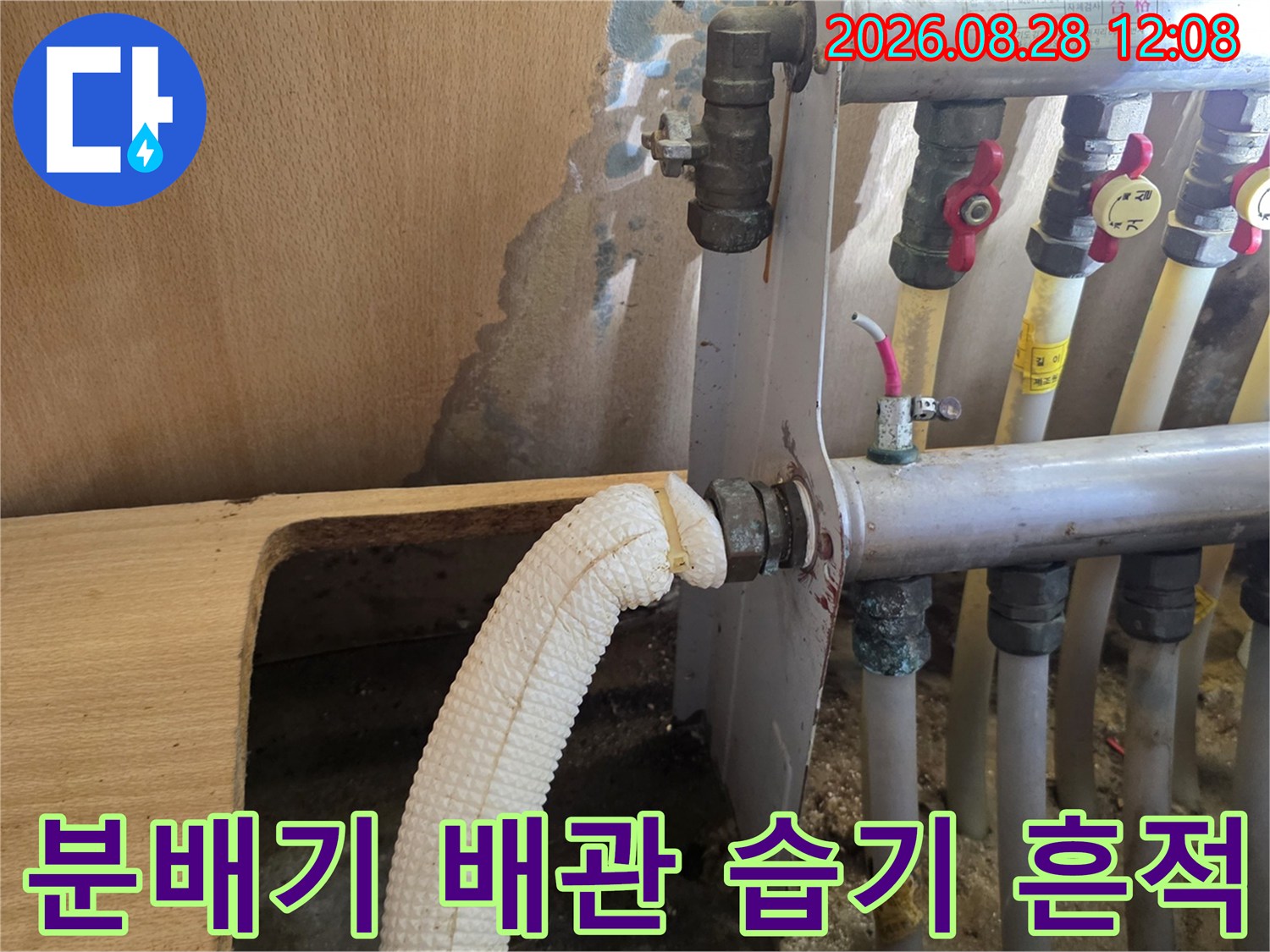 싱크대 하부 벽면의 물에 젖은 얼룩과 분배기 배관 상세 사진입니다.