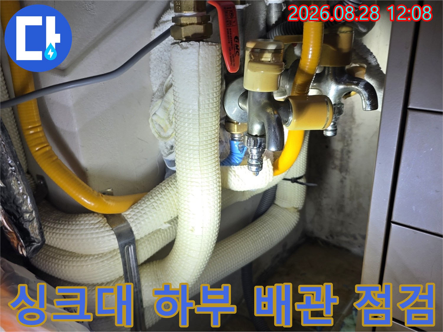 흰색 보온재와 노란색 호스가 연결된 싱크대 하단 배관 부위