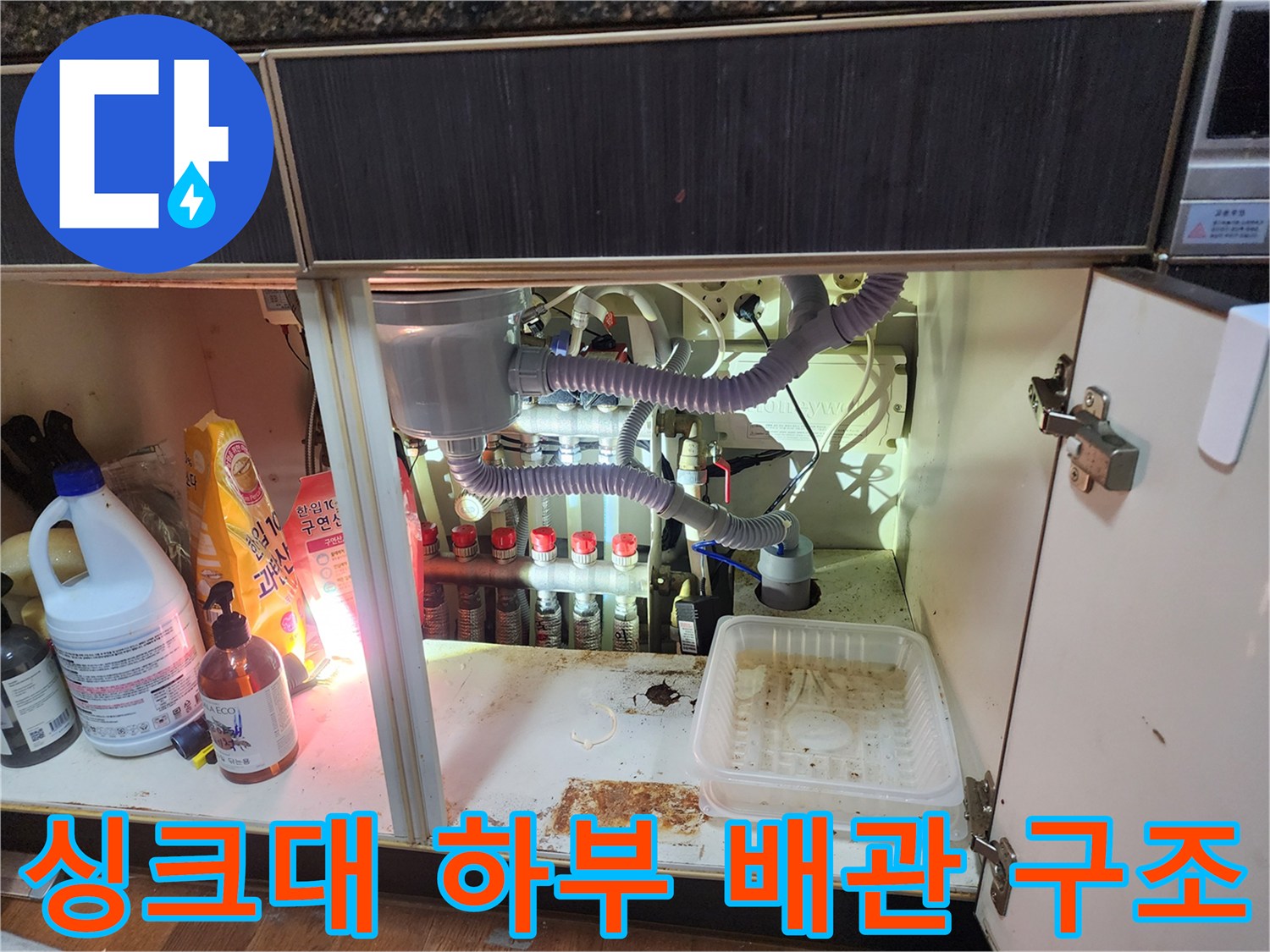 복잡하게 연결된 에어컨 배수 호스와 싱크대 하단 배관의 정밀 점검 모습