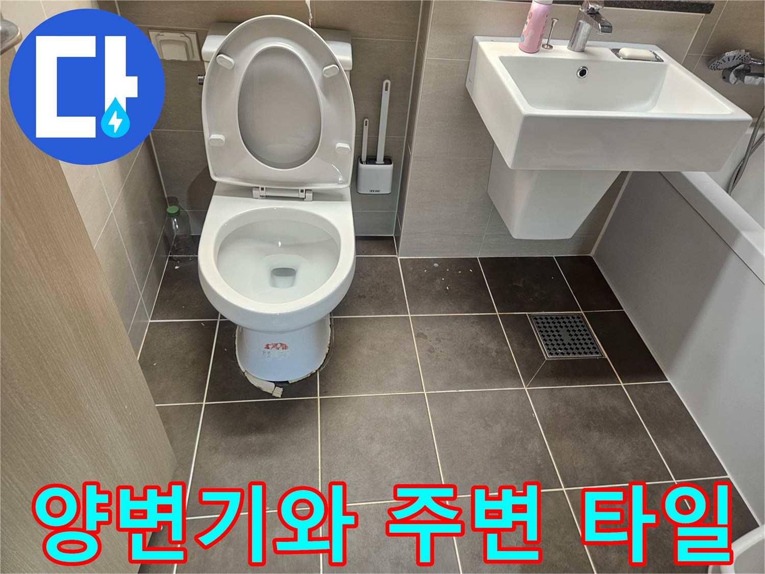 회색 타일 벽면과 양변기가 설치된 화장실 내부 모습입니다.