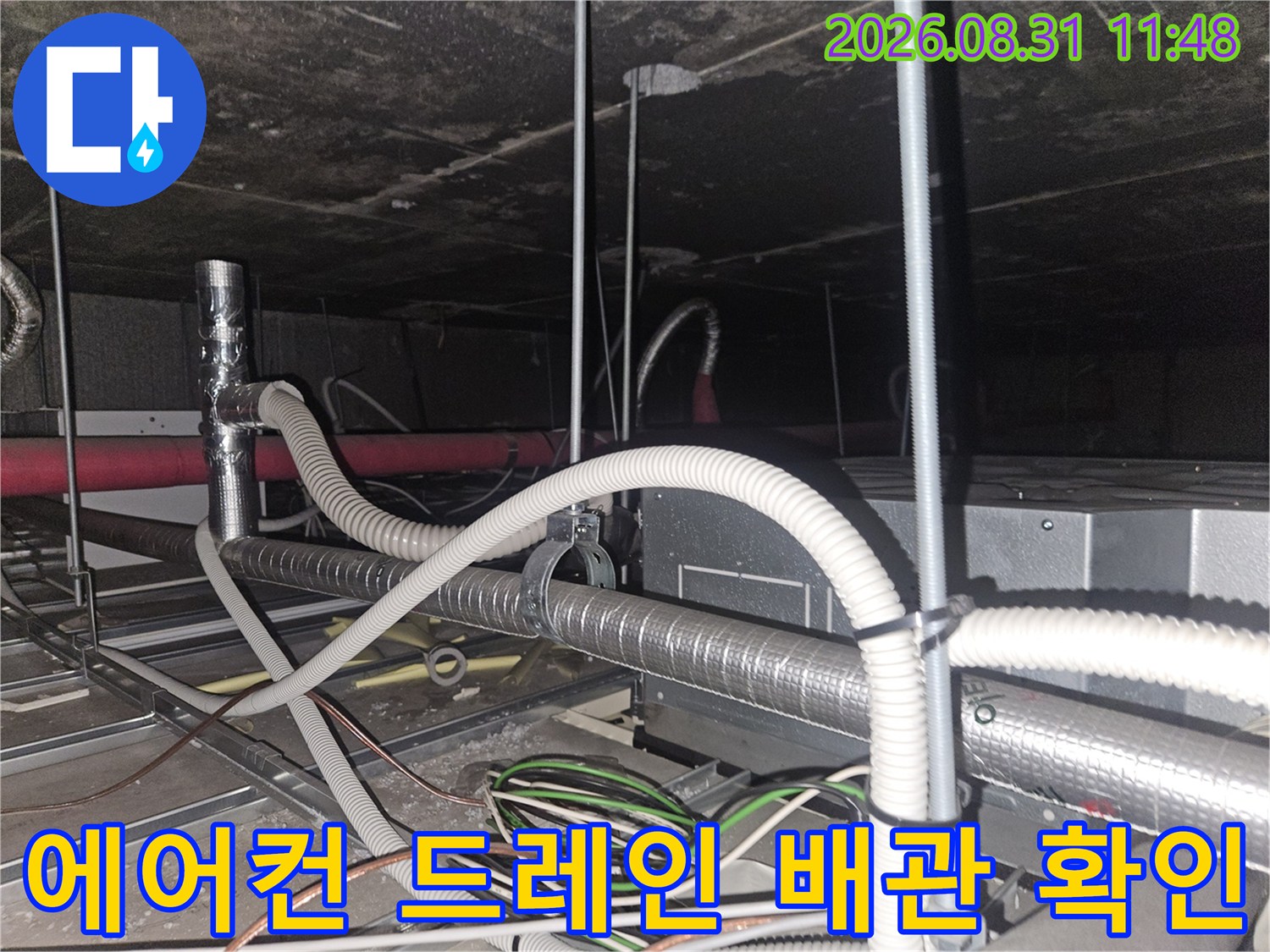 복잡하게 얽힌 천장 내부의 에어컨 배수 호스와 은색 보온재 배관 사진