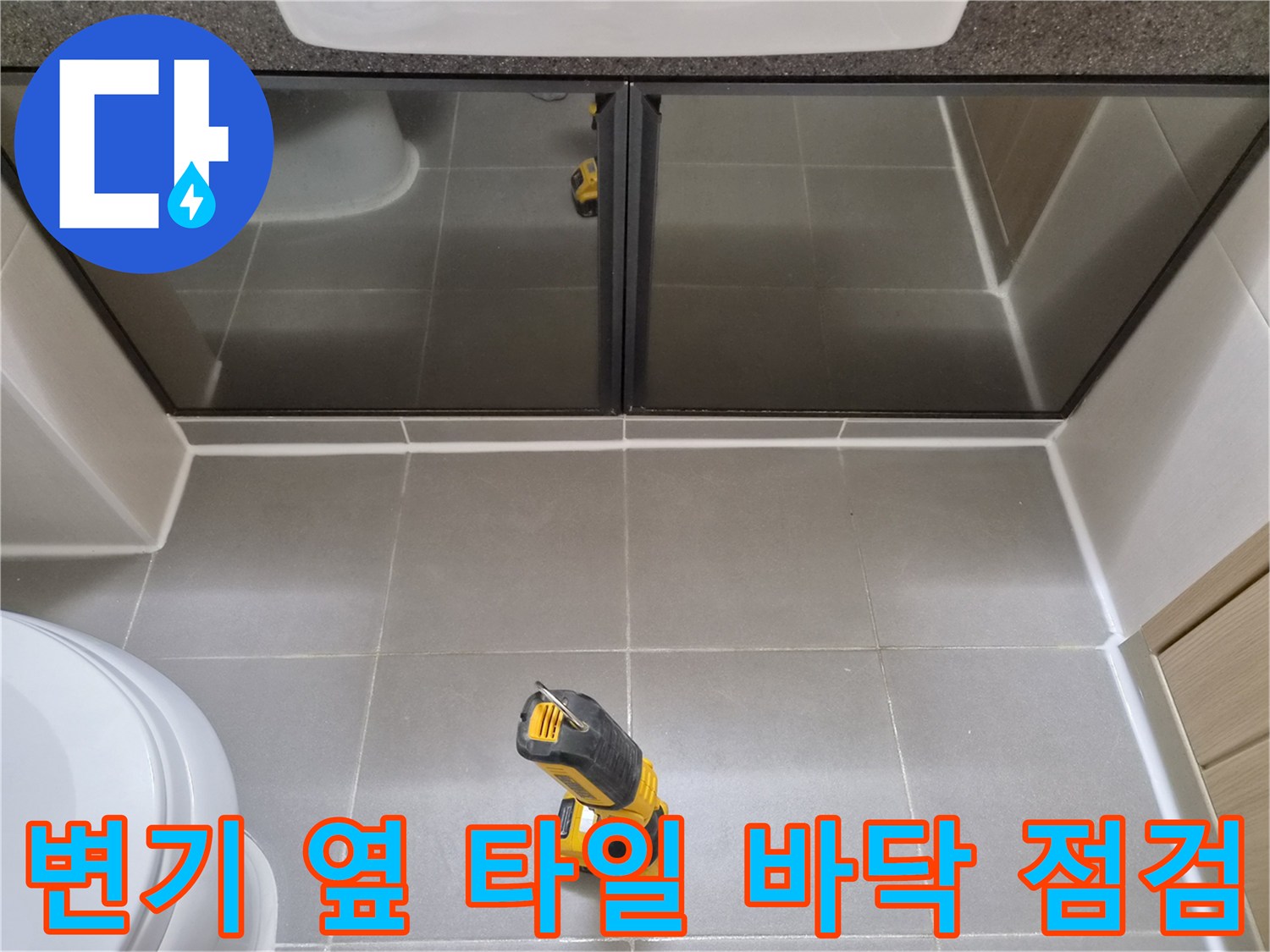 욕실 타일 위에 놓인 노란색 작업용 드릴