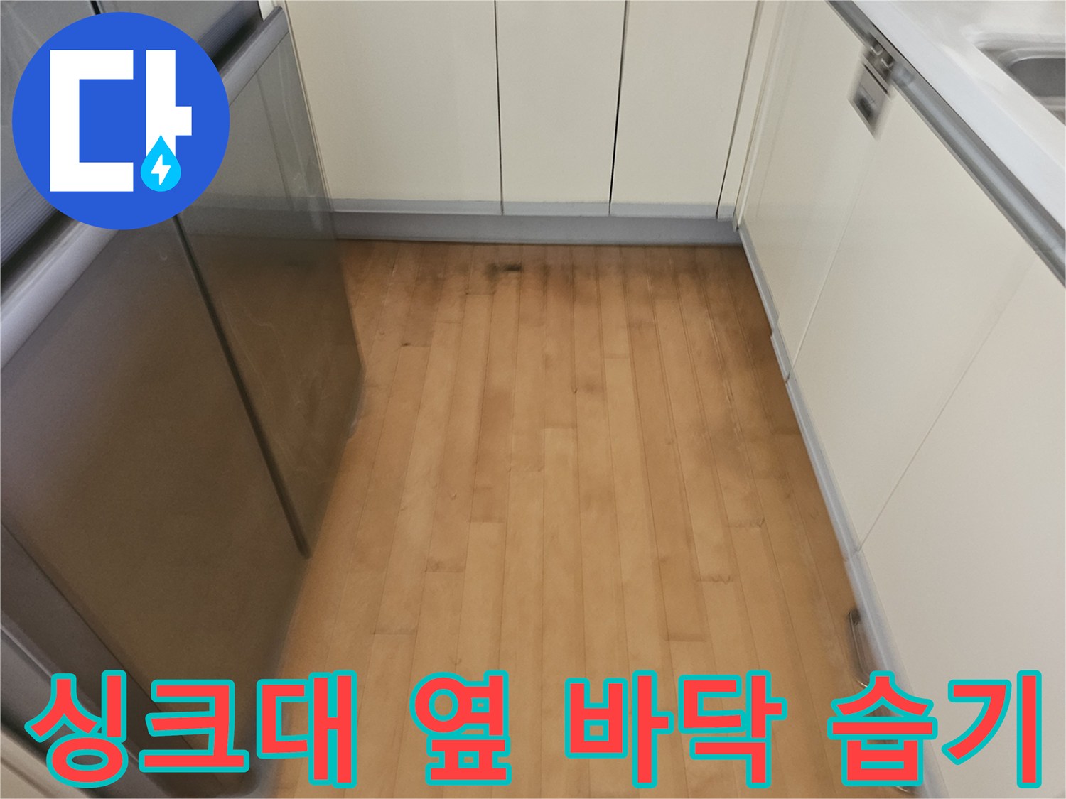 냉장고와 싱크대 사이 바닥 마감재에 나타난 습기 흔적과 변색 현상