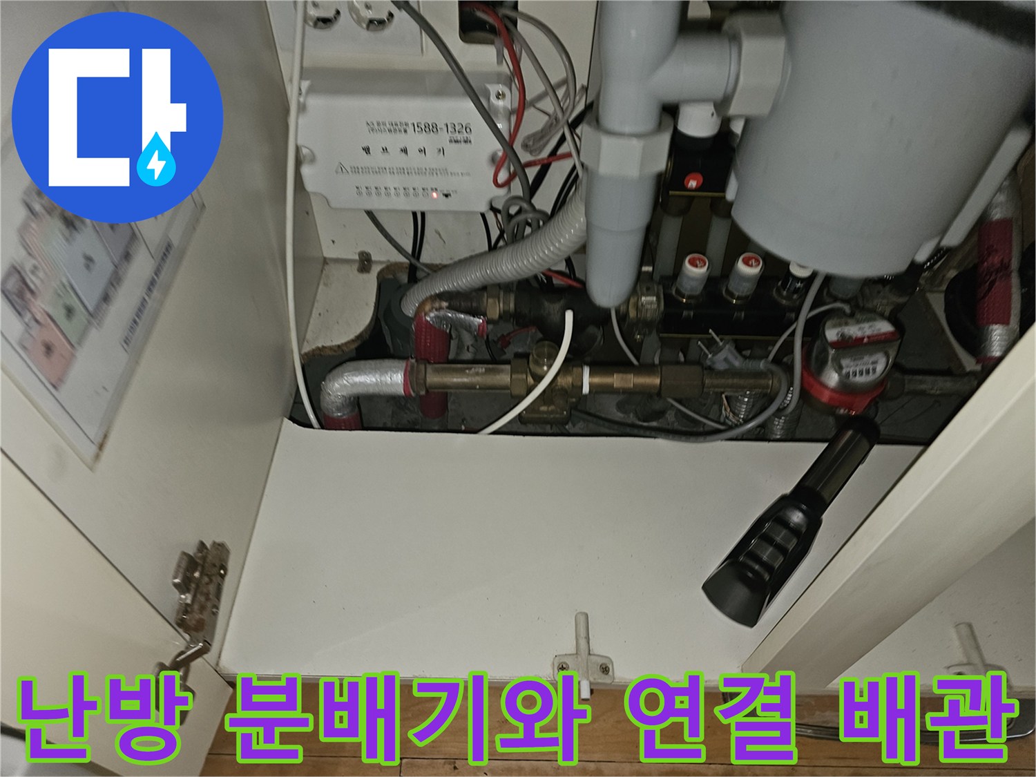 싱크대 하단에 위치한 난방 분배기 및 각종 배관의 모습