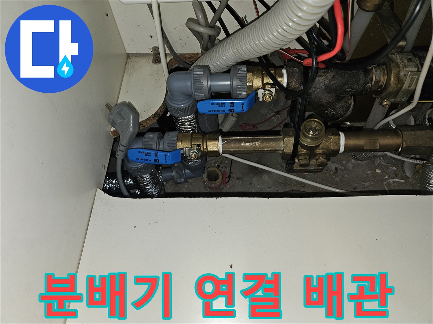 파란색 밸브와 금속 관이 복잡하게 설치된 주방 하부장 내부