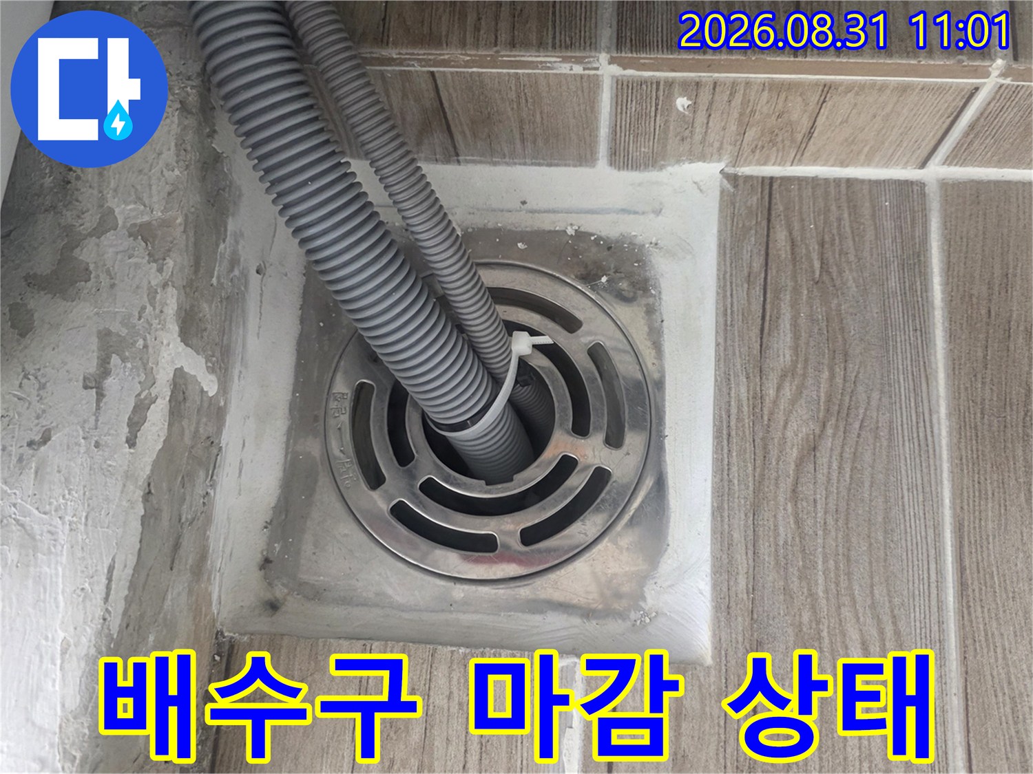 세탁실 바닥 배수구 주변의 타일과 유가 사이 틈새를 근접 촬영한 사진입니다.