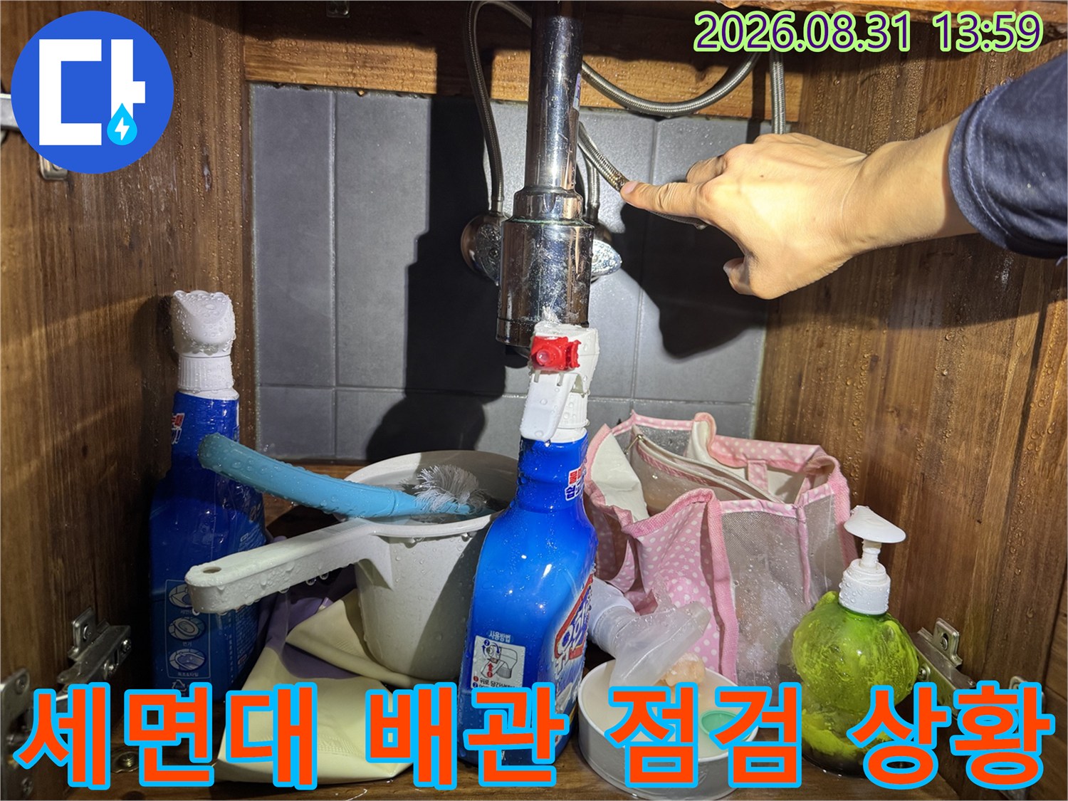세면대 아래 수전 연결 부위와 밸브를 손으로 점검하는 모습