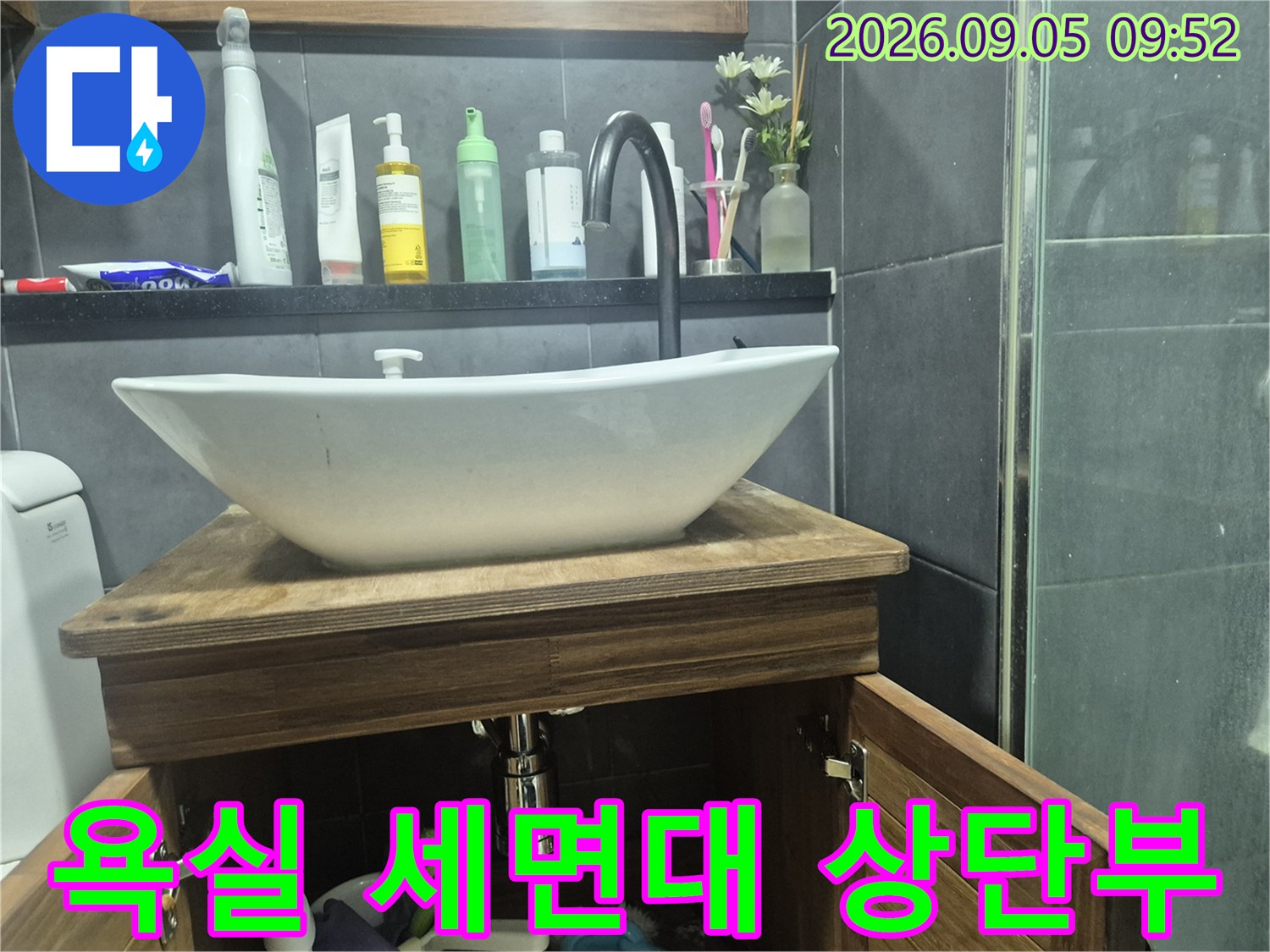 하얀색 세면대와 검은색 수전이 설치된 욕실 내부 사진