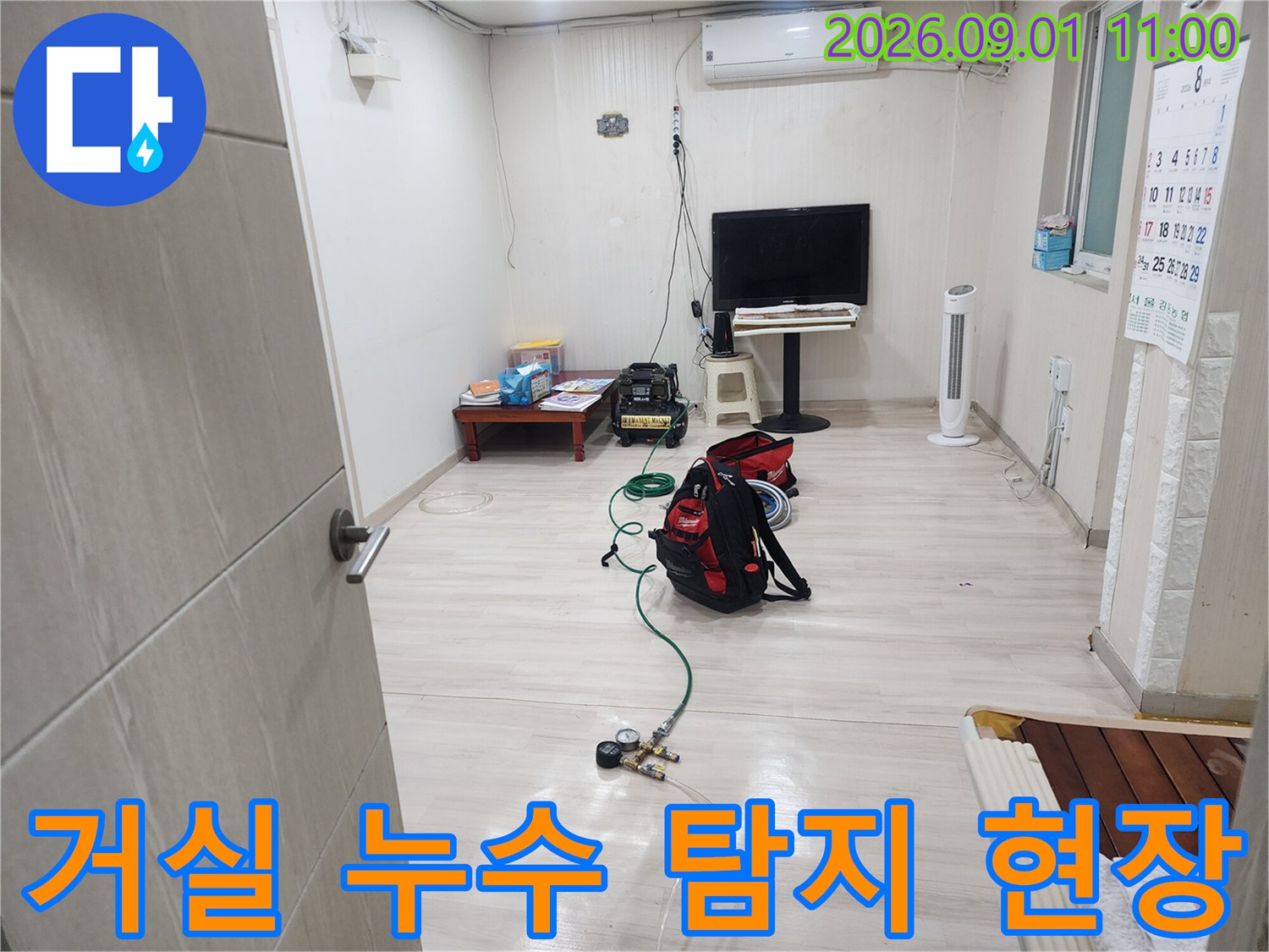 가스 탐지 장비를 거실 바닥에 배치하여 진행하는 배관 누수 검사 장면