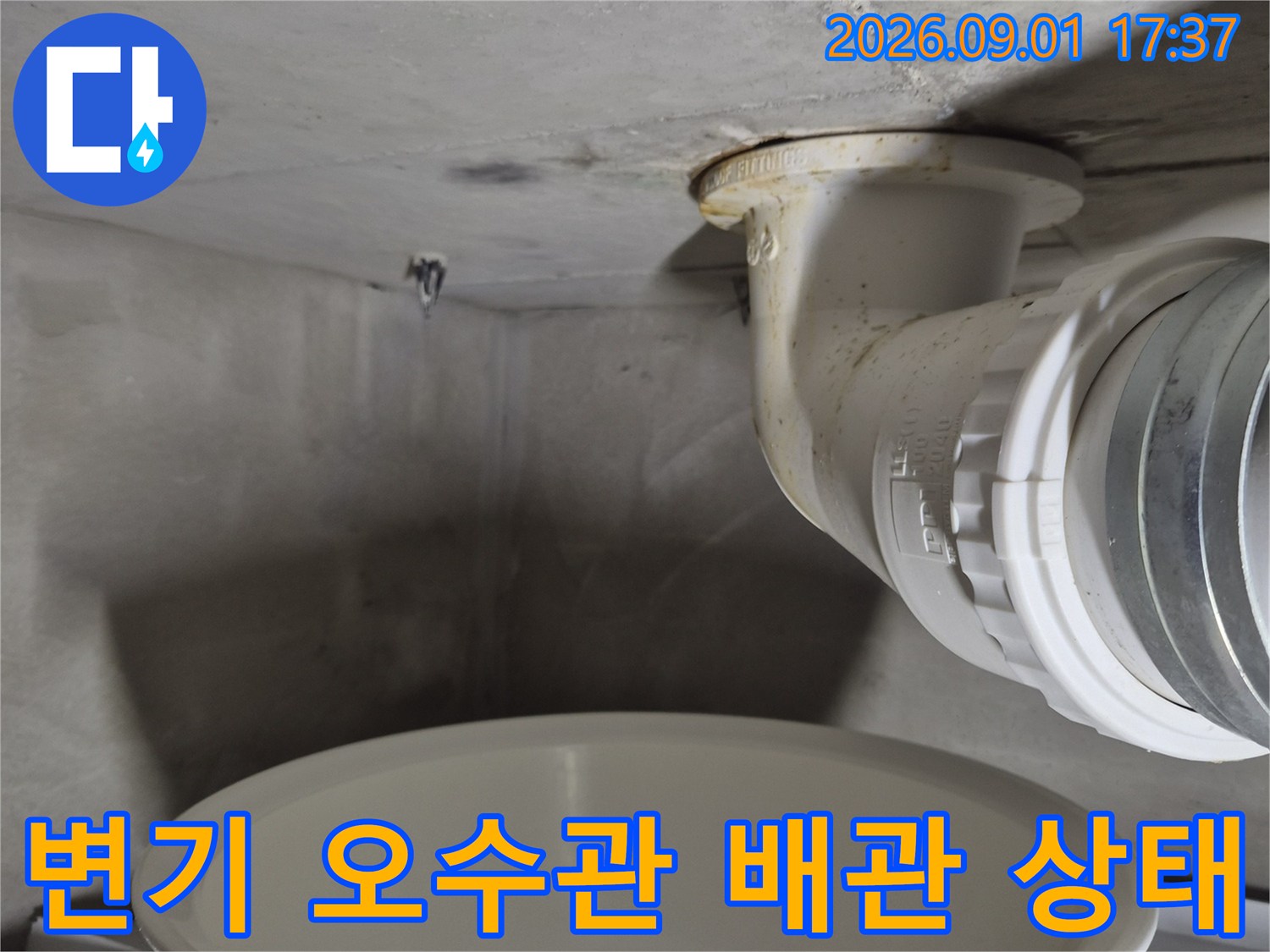 변기 아래쪽 오수관 연결 부위의 틈새와 벽면 접촉부를 근접 촬영했습니다.