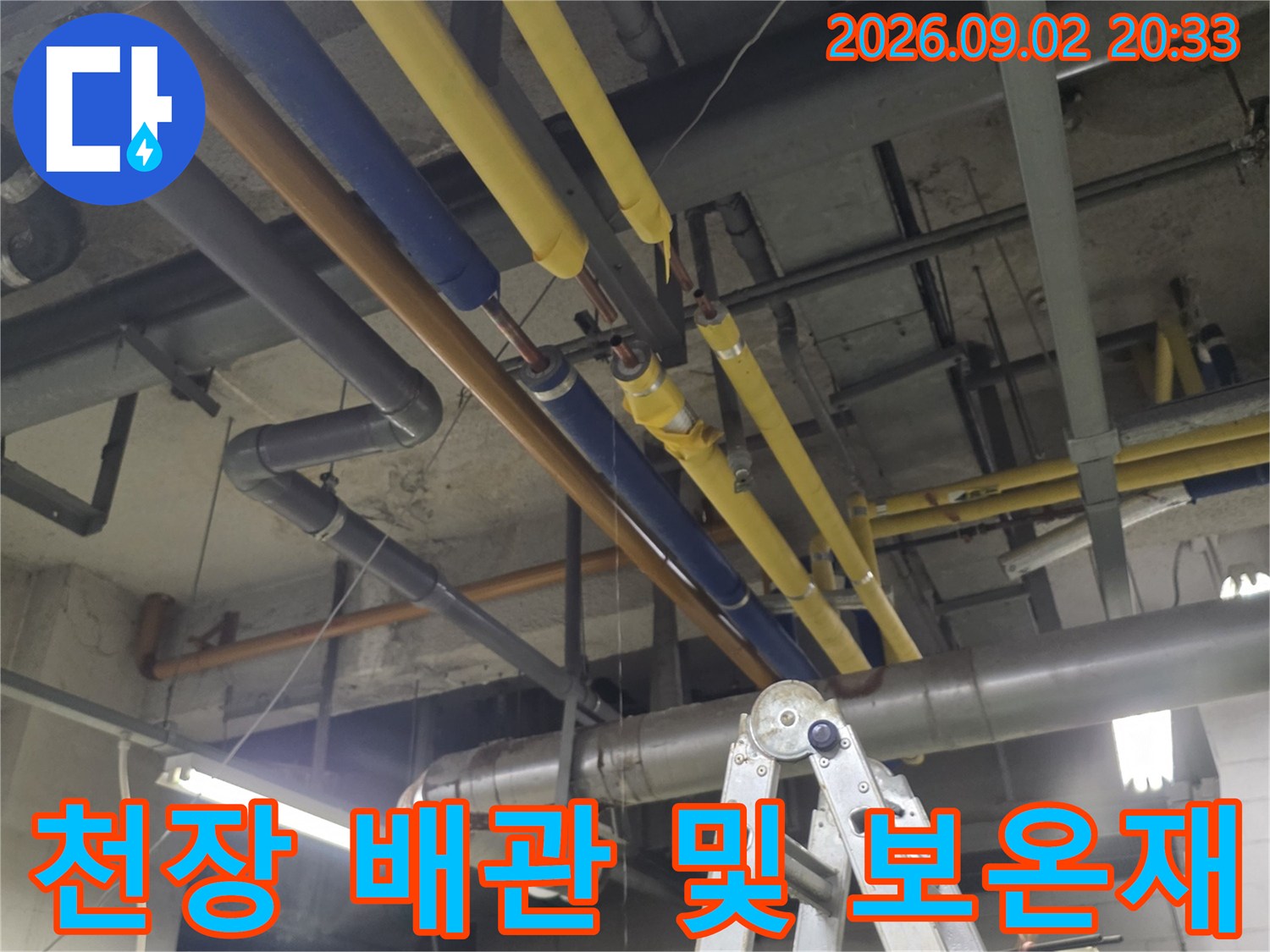 복잡하게 얽힌 천장 내부의 노란색과 파란색 배관 라인