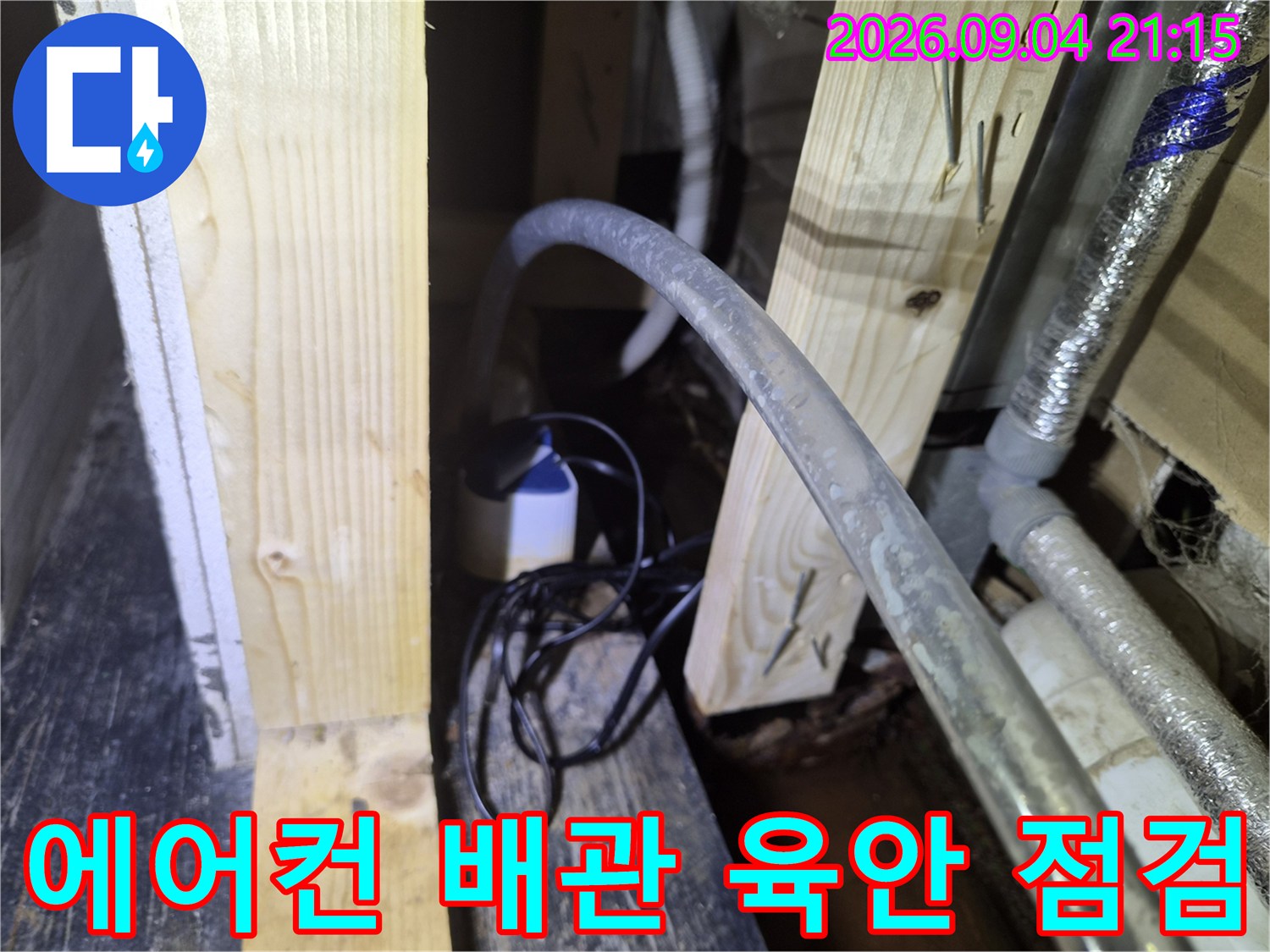 천장 목재 각재와 에어컨 드레인 호스의 근접 촬영 모습