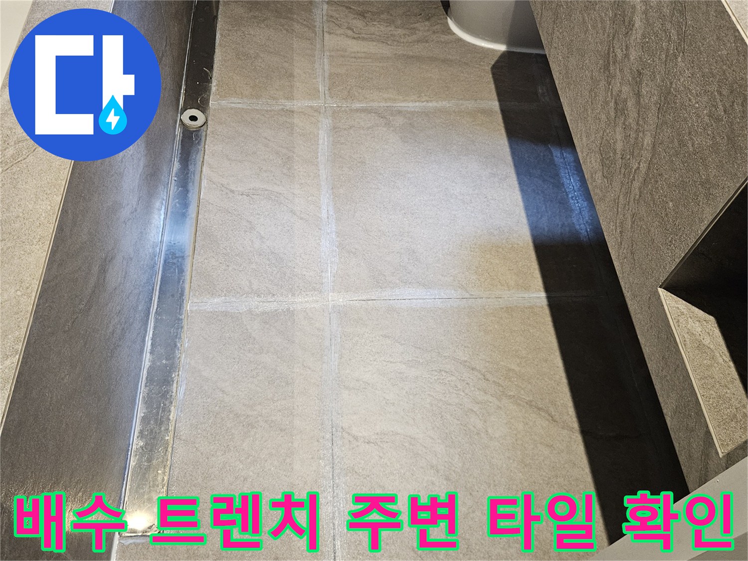 욕실 바닥의 길쭉한 배수 트렌치와 대리석 타일 마감 상세샷