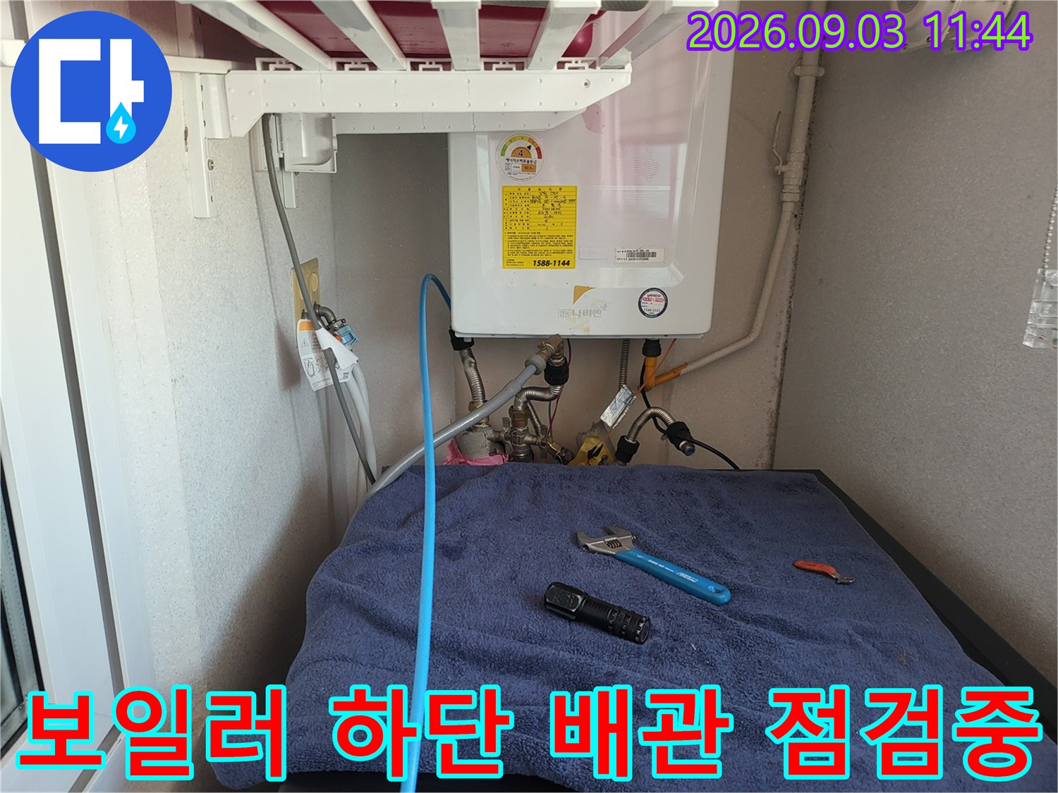 보일러 아래 배관과 함께 놓여있는 작업용 렌치와 조명기구