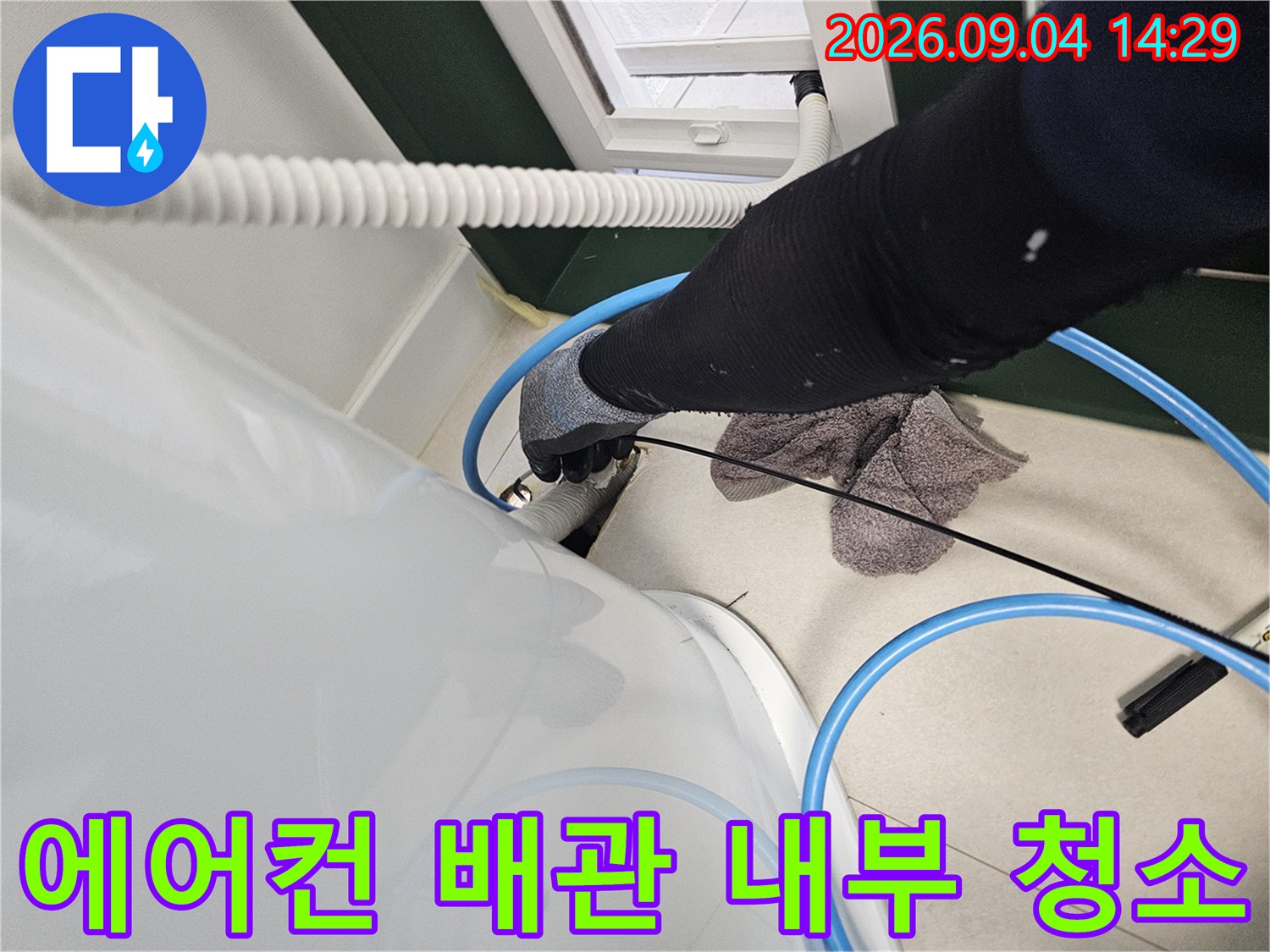 파란색 호스를 사용하여 에어컨 매립 배관의 잔수를 흡입하는 모습입니다.