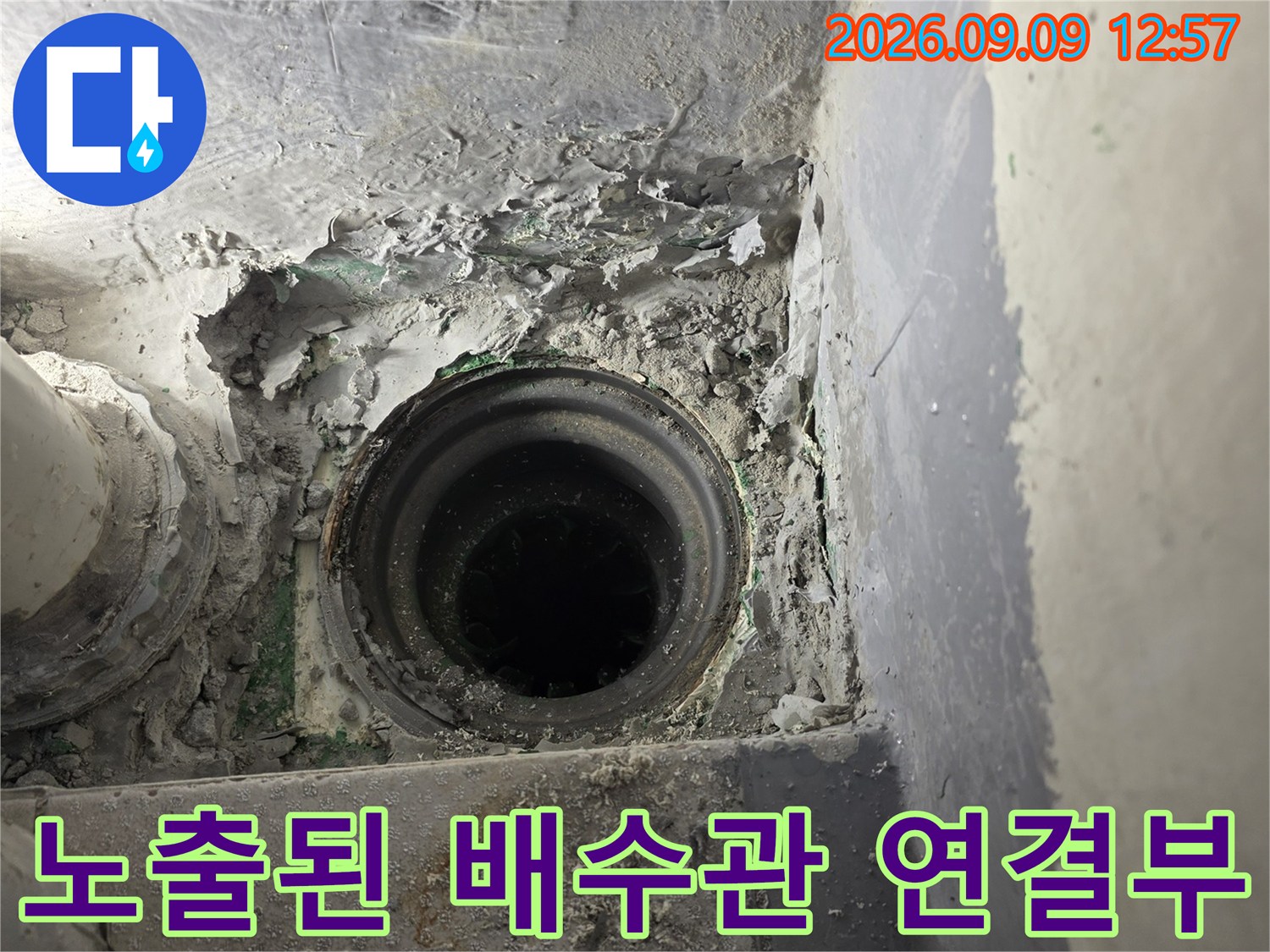 배관 주변의 부서진 마감재와 노출된 배수관의 모습입니다.