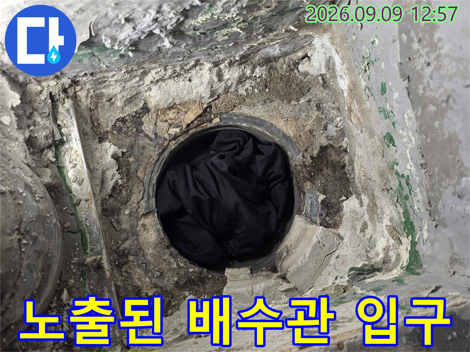 배수구 주변의-파손된 시멘트와 노출된 배관입니다