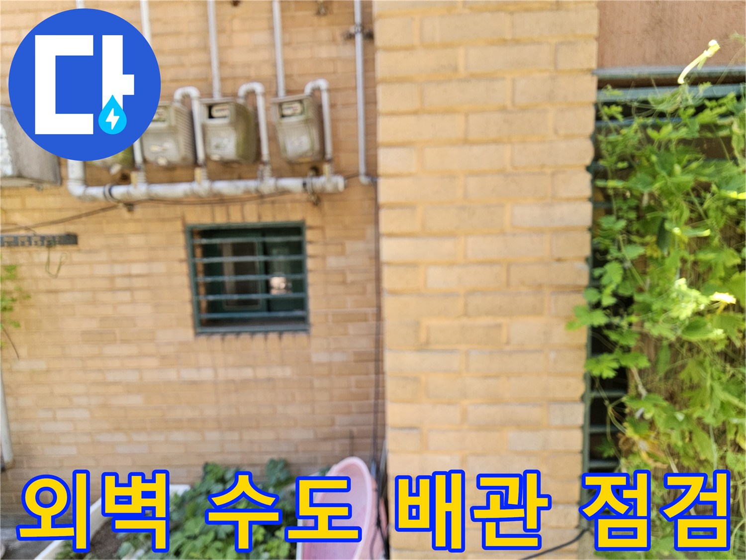 건물 외벽 벽돌 면에 설치된 수도 계량기와 연결 배관입니다.