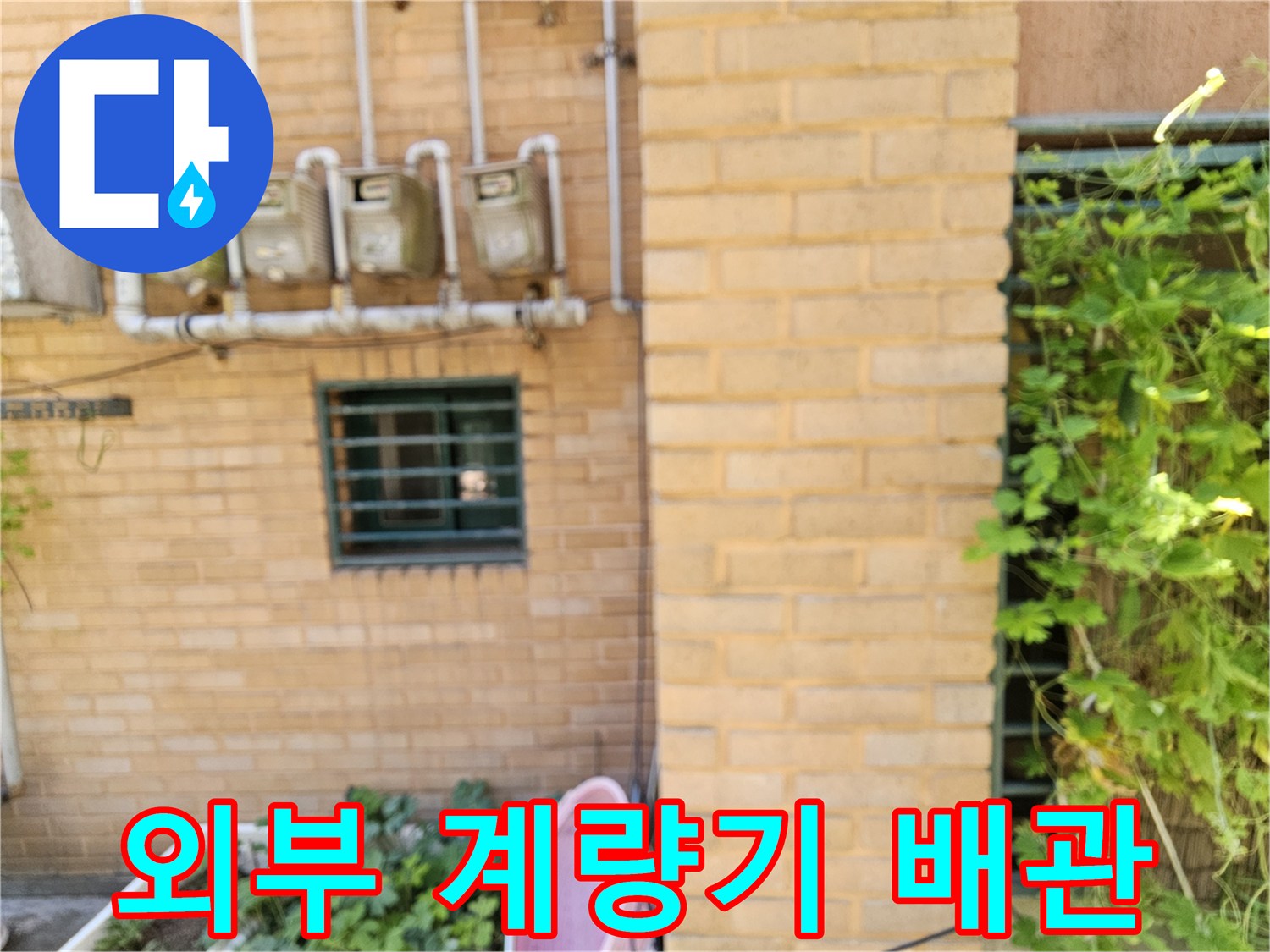 건물-외벽-벽돌-사이로-노출된-수도-계량기와-배관
