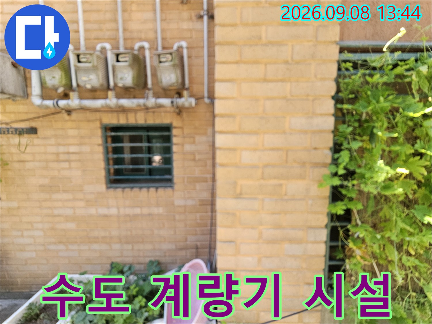 주택 외벽에 노출된 수도 계량기와 연결 배관의 상세 모습