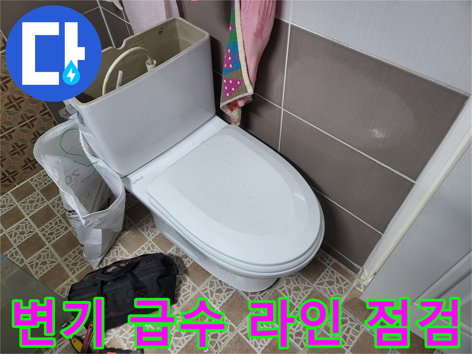 변기 측면 밸브와 연결된 호스 및 타일 벽면 사진