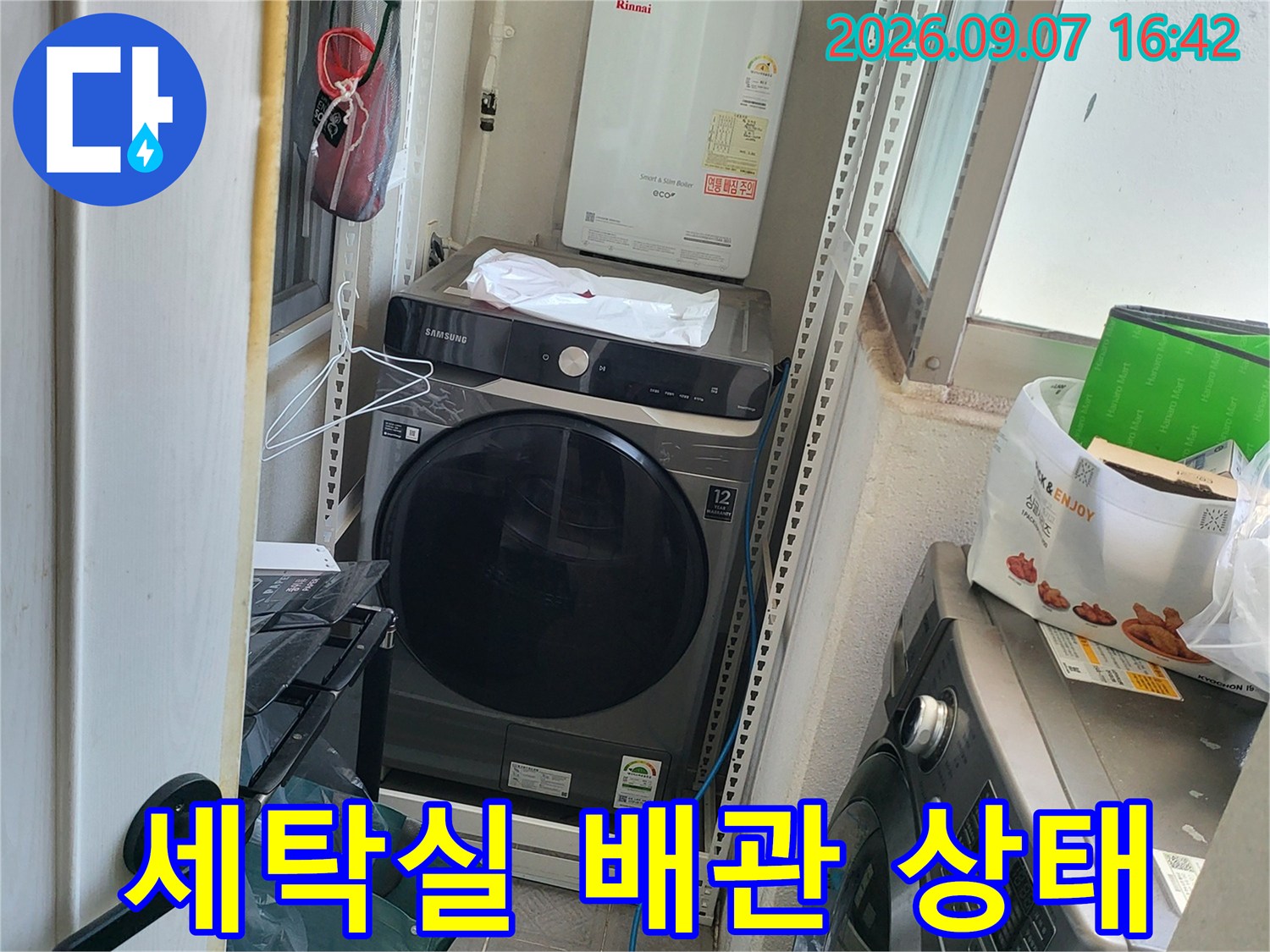 세탁기와 선반 아래 배관 연결 부위를 촬영한 사진입니다.