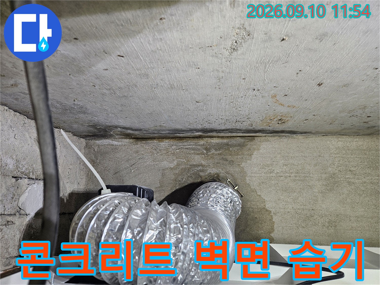습기로 인해 어둡게 변한 콘크리트 천장과 은색 배관 구조물