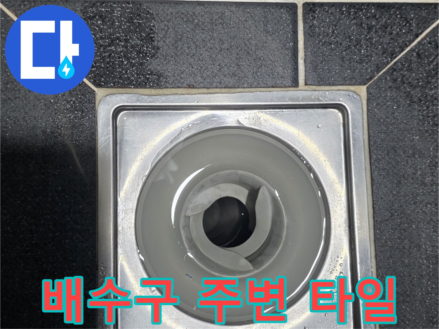 물기가 맺힌 화장실 배수구와 검은색 바닥 타일